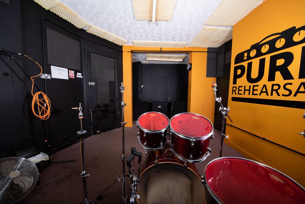 Rehearsal space with drum set in Pure Rehearsal Studios for music events.