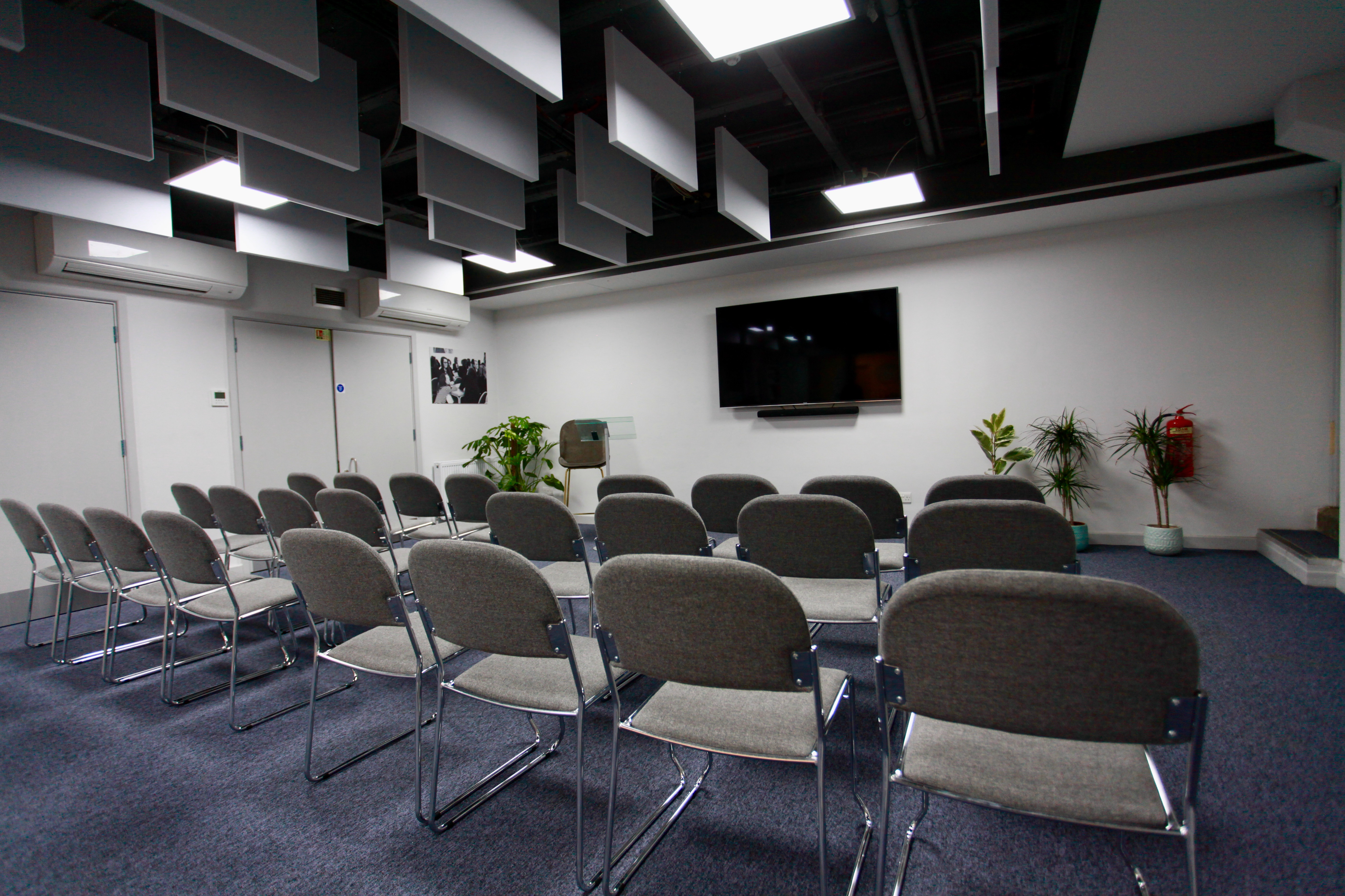 Meeting space at Neal Street Espresso with chairs and wall-mounted screen for workshops.