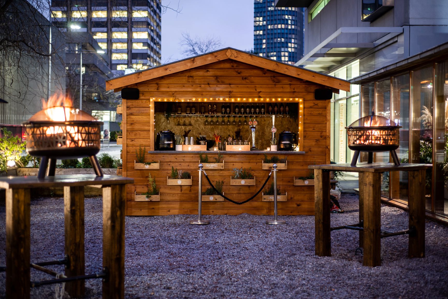 Stylish outdoor bar with fire pits, perfect for events and gatherings.