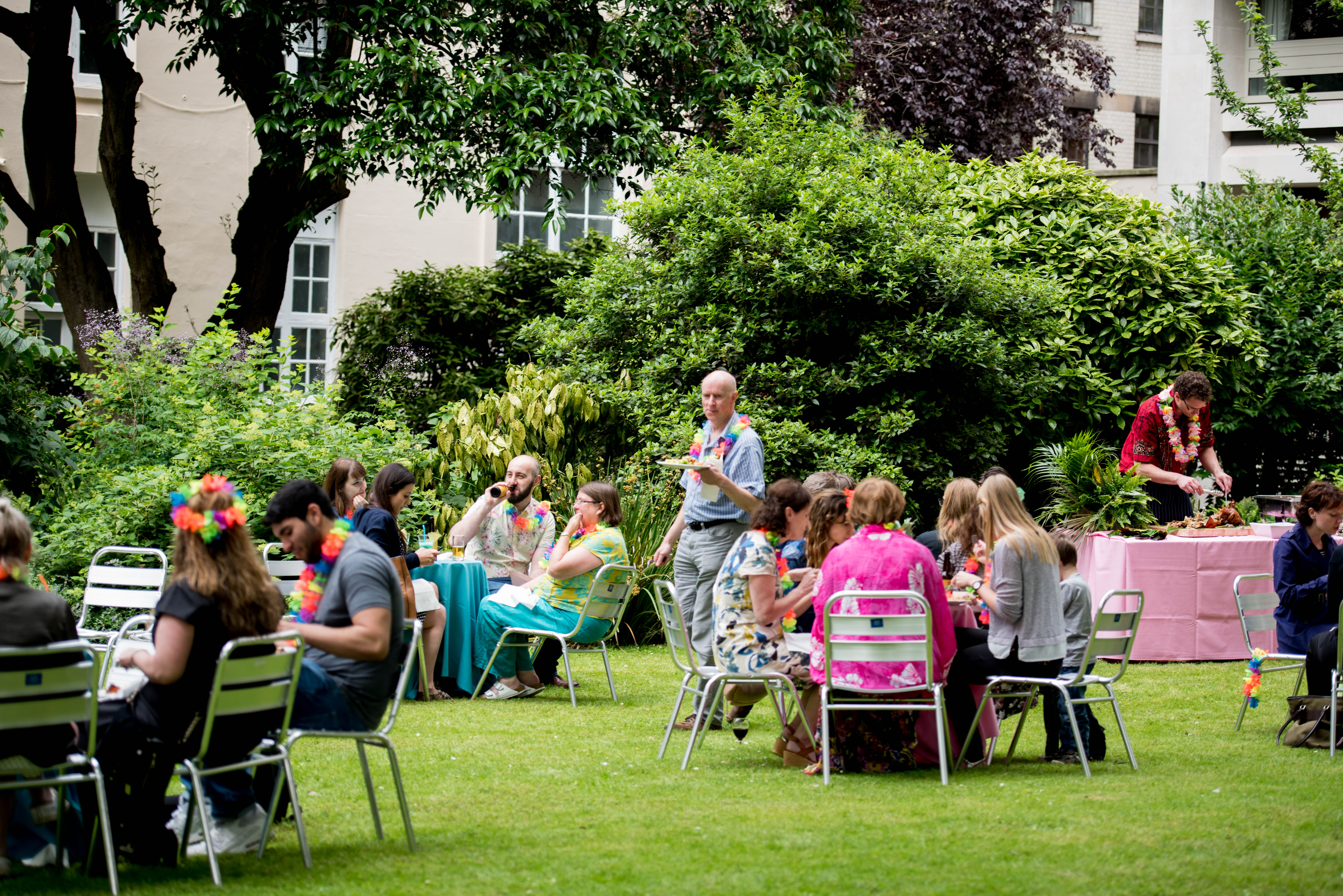 Summer party in Westminster garden with colorful leis, ideal for networking and team-building.