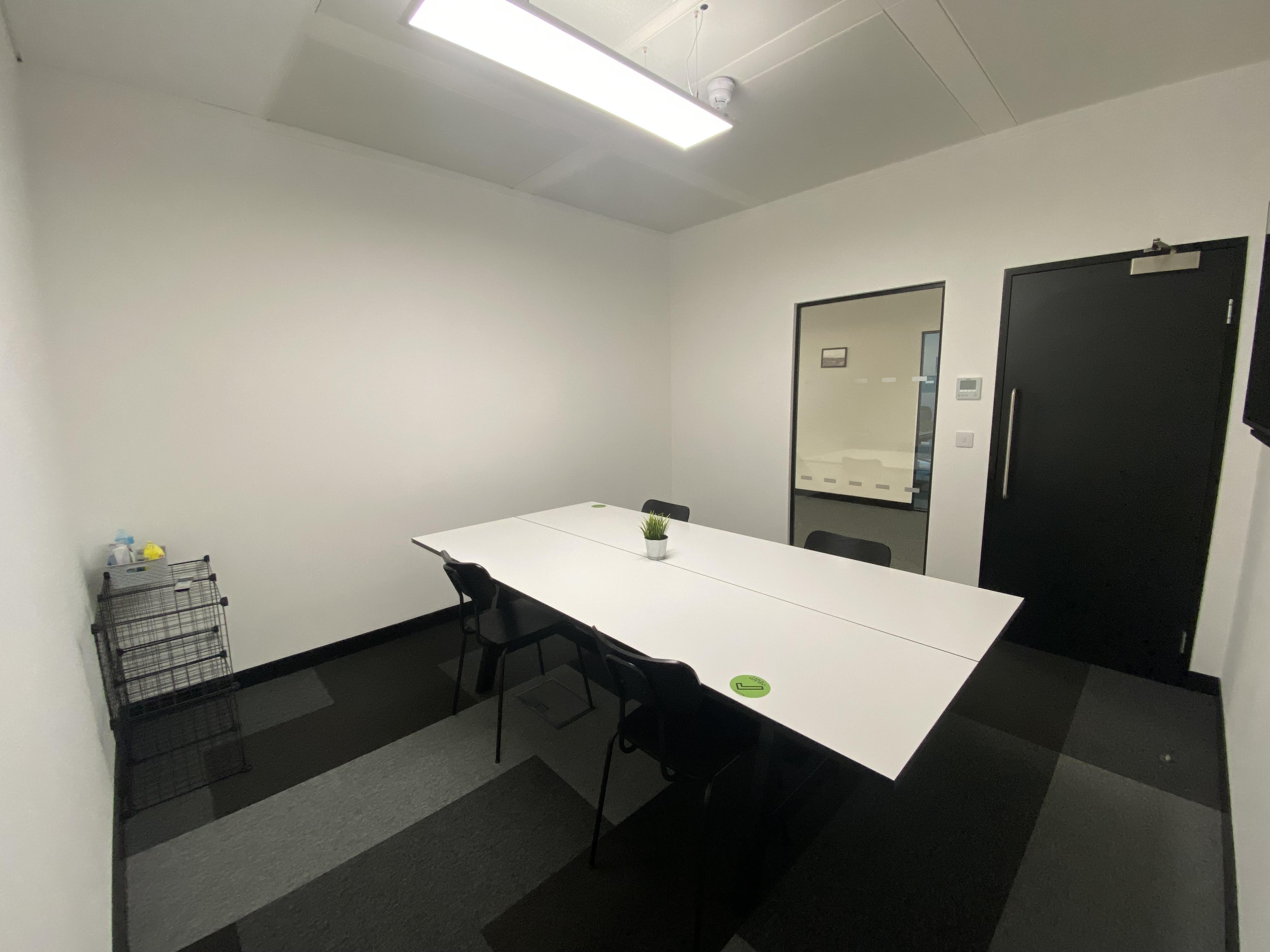 Minimalist meeting room at SPS2, featuring a white table and black chairs for brainstorming.