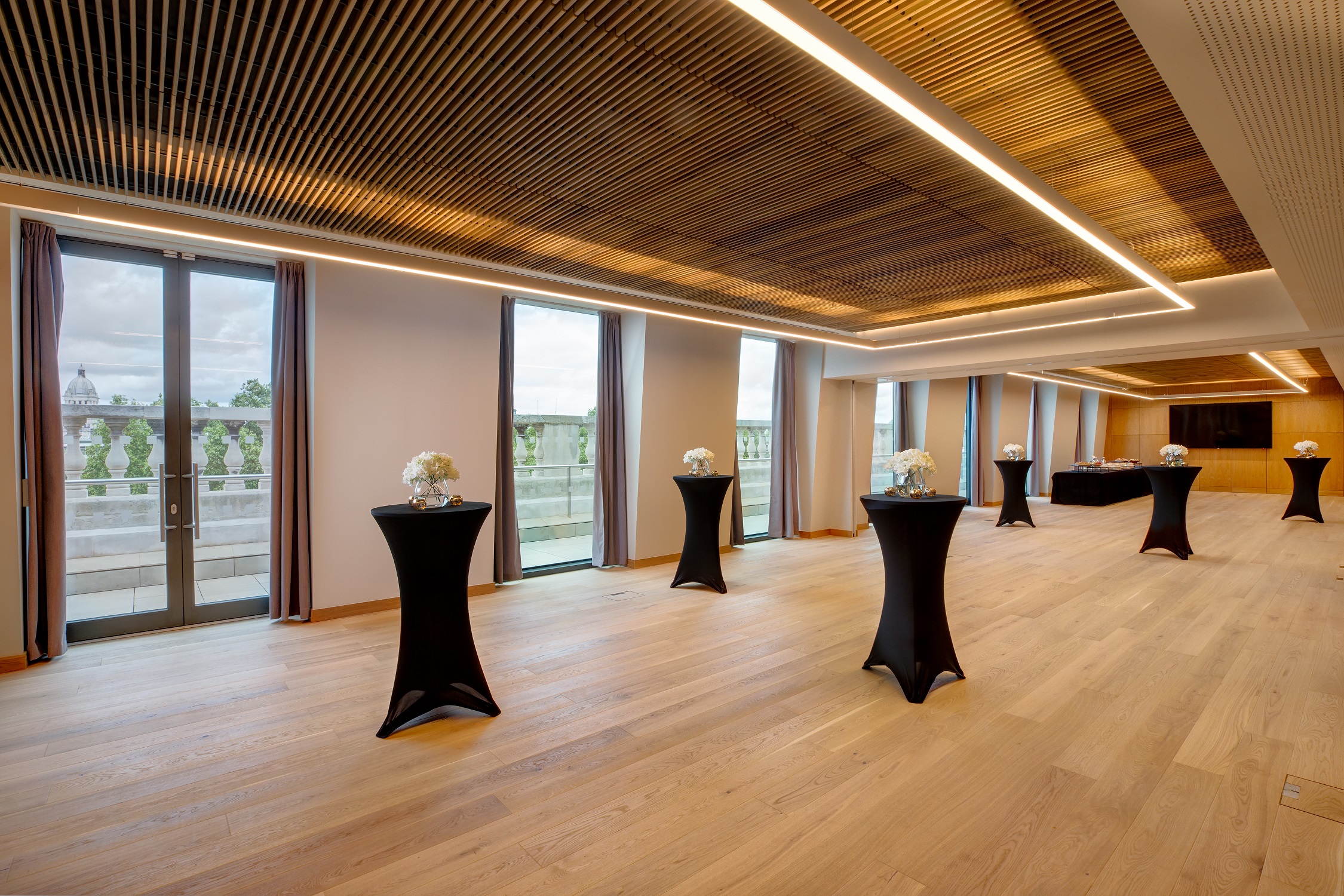 Modern event space with wooden flooring and large windows, perfect for networking events.