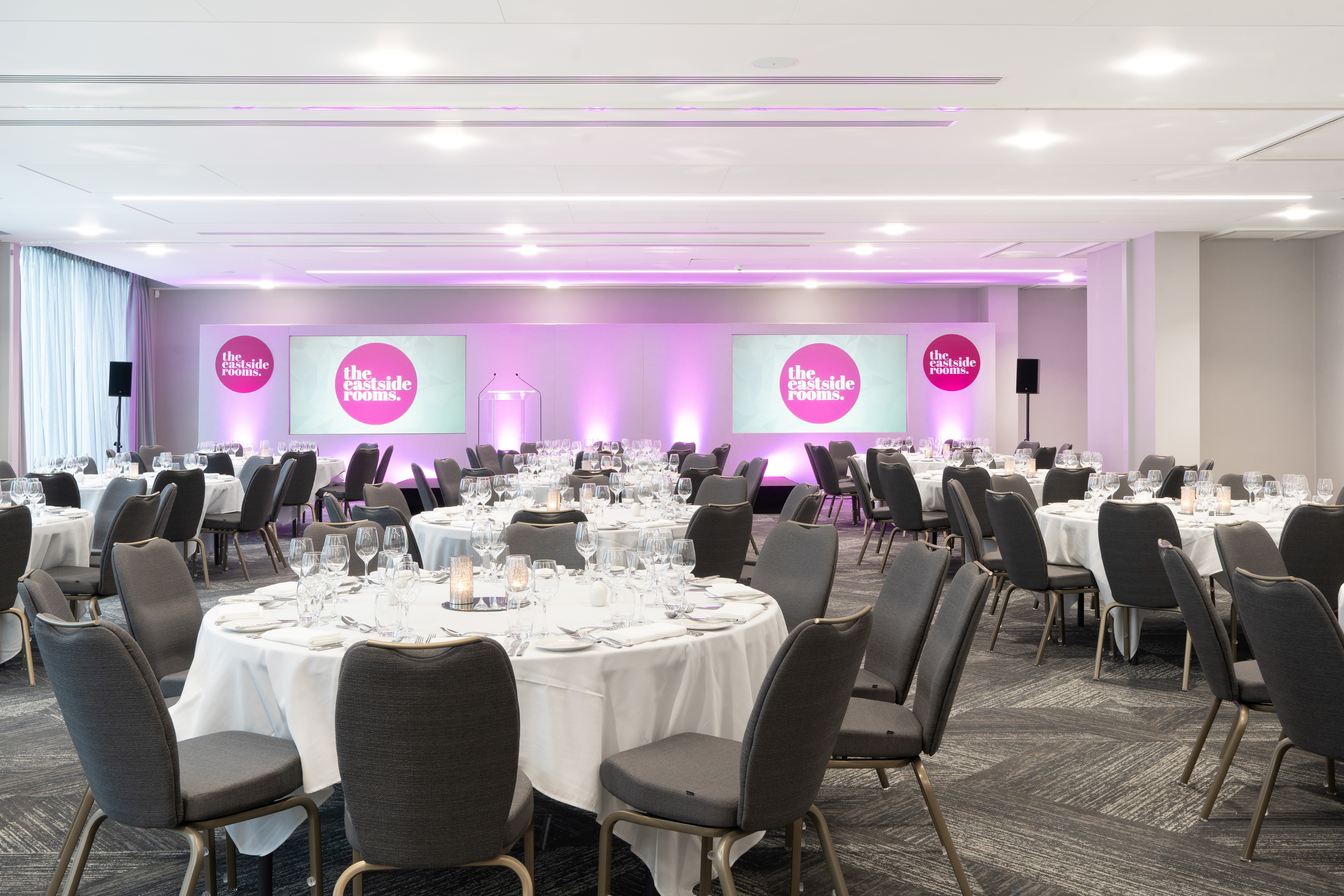 Elegant event space with round tables, ideal for corporate gatherings and conferences.