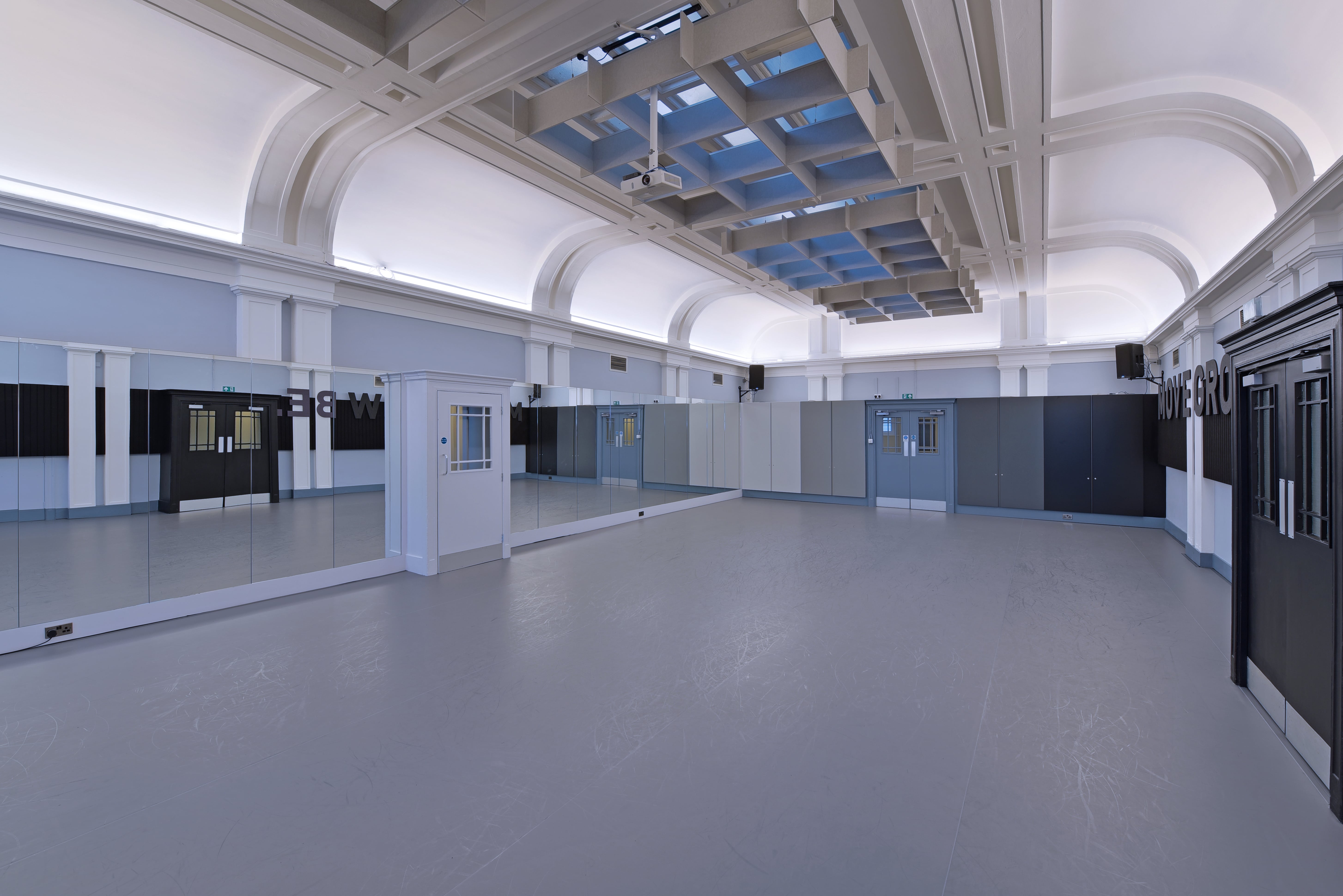 Spacious event venue with high ceilings and mirrors, perfect for workshops and fitness classes.