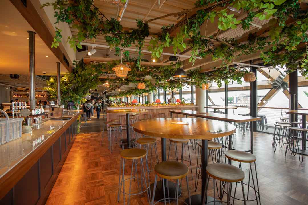 Stylish event space with modern bar and greenery, perfect for gatherings and networking.