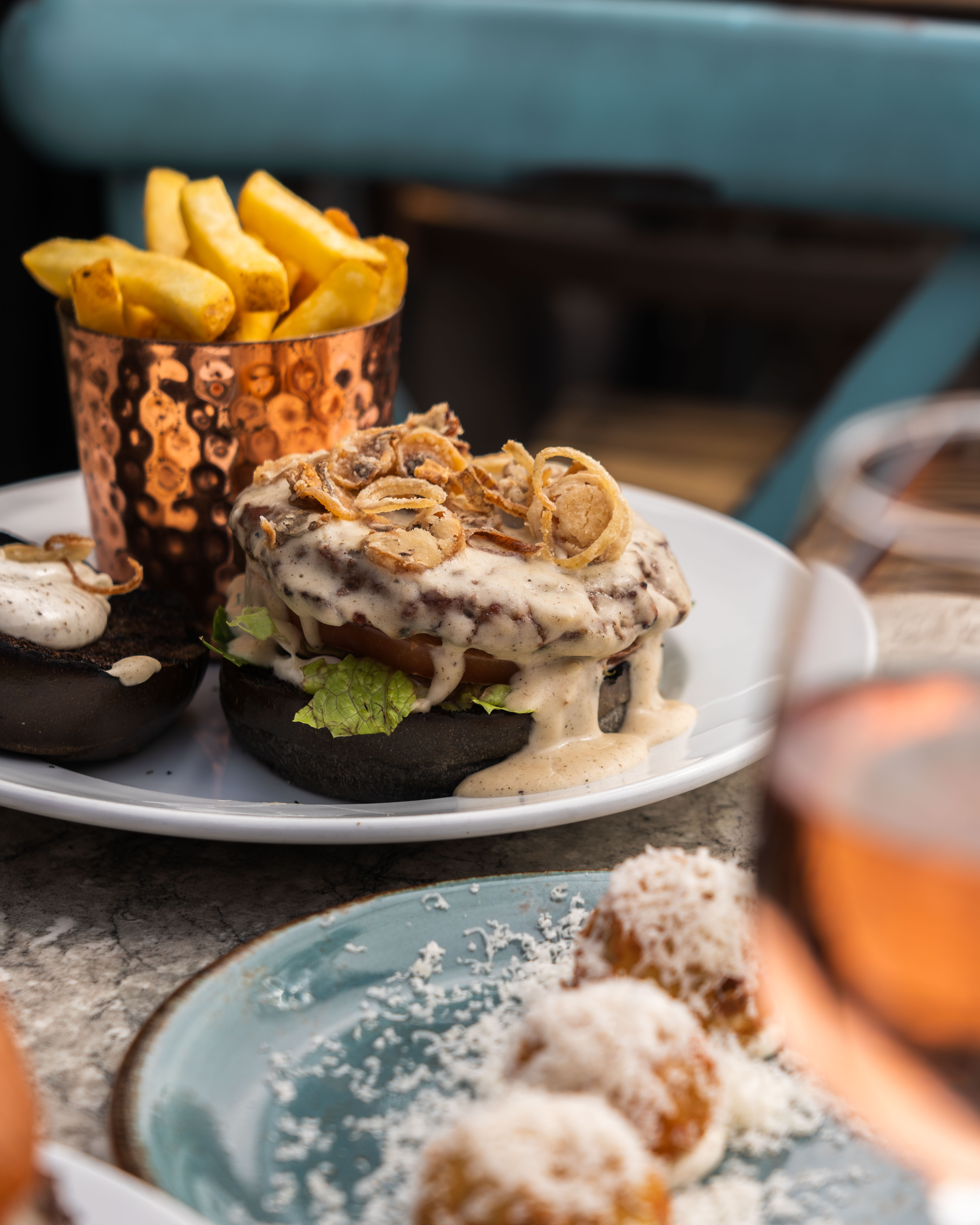 Gourmet burger with crispy onions and fries at Terrace, Paradiso London event catering.