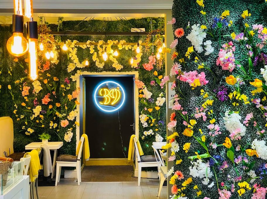Vibrant event venue with floral wall and neon sign, perfect for celebrations.