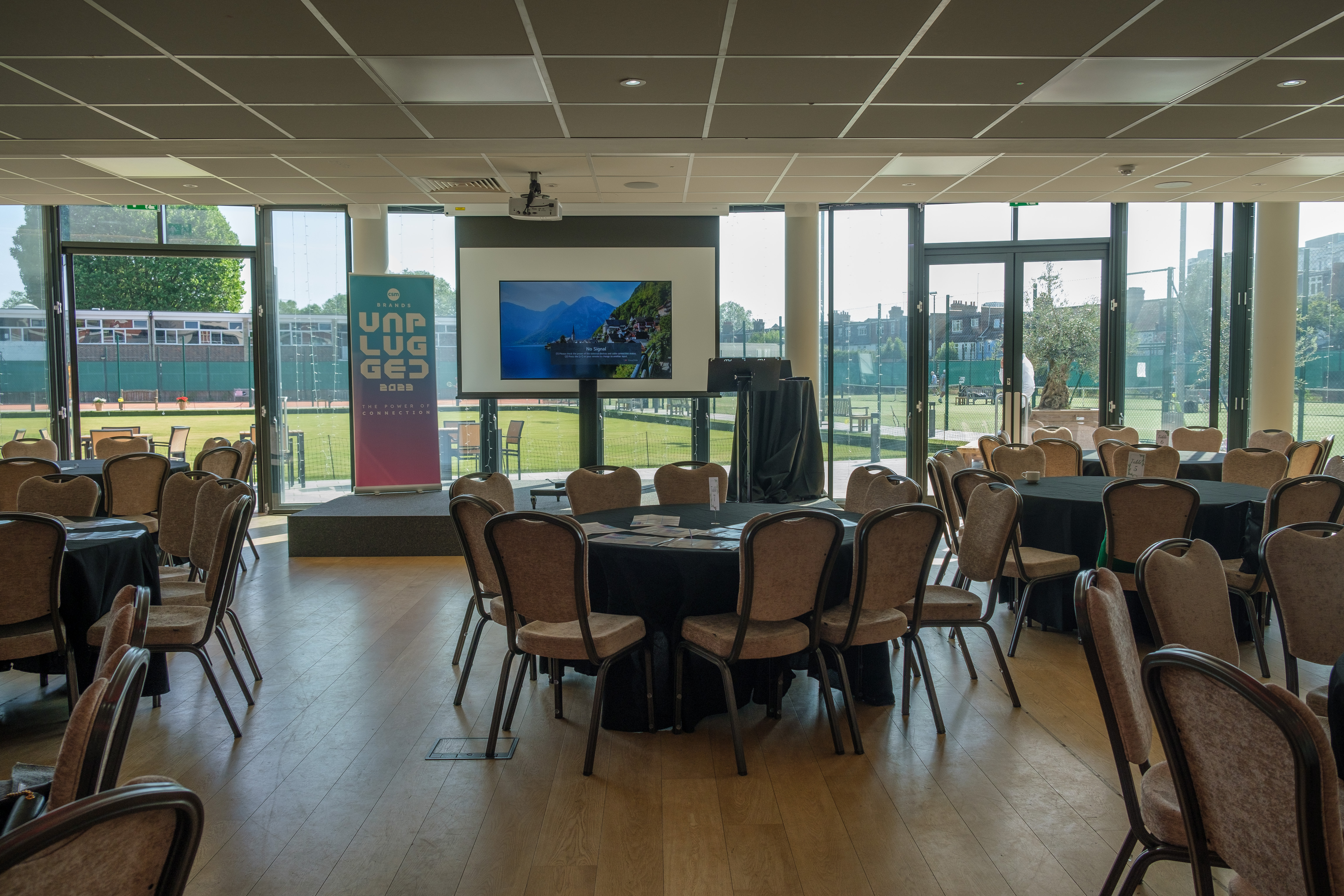 Oval Room at Parsons Green Club, set for a meeting with round tables and presentation screen.