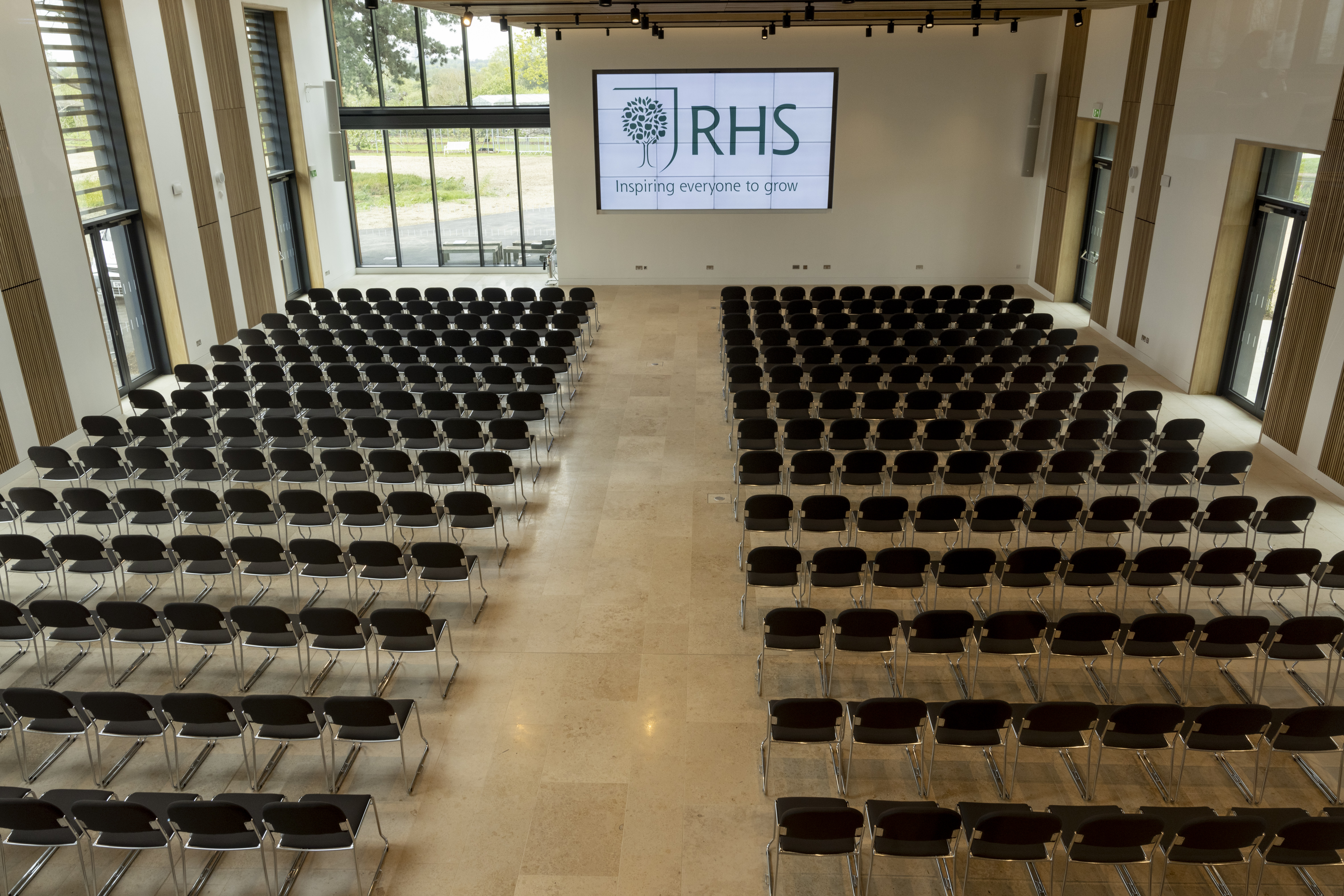Hilltop Garden Room at RHS Wisley, spacious venue for conferences with black chairs.