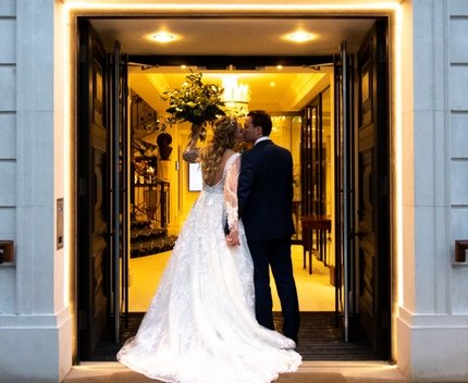 Couple kissing at elegant wedding venue entrance, showcasing romance and luxury.