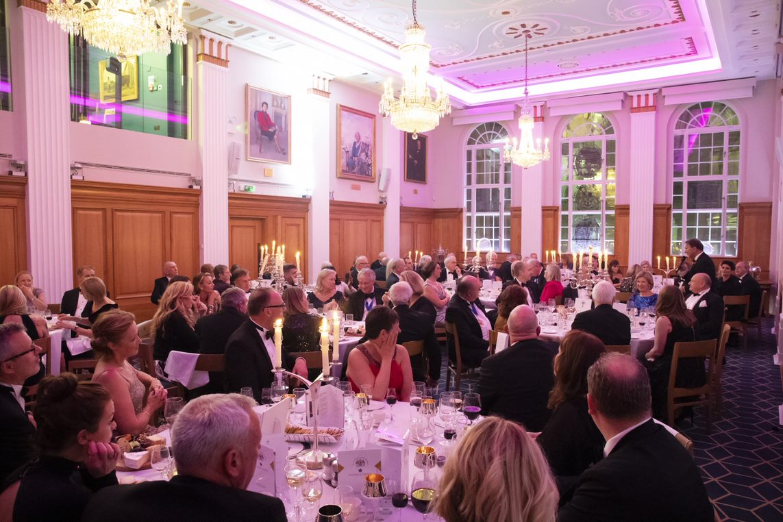 Elegant gala at 87 Barts Close with well-dressed attendees and warm ambiance.