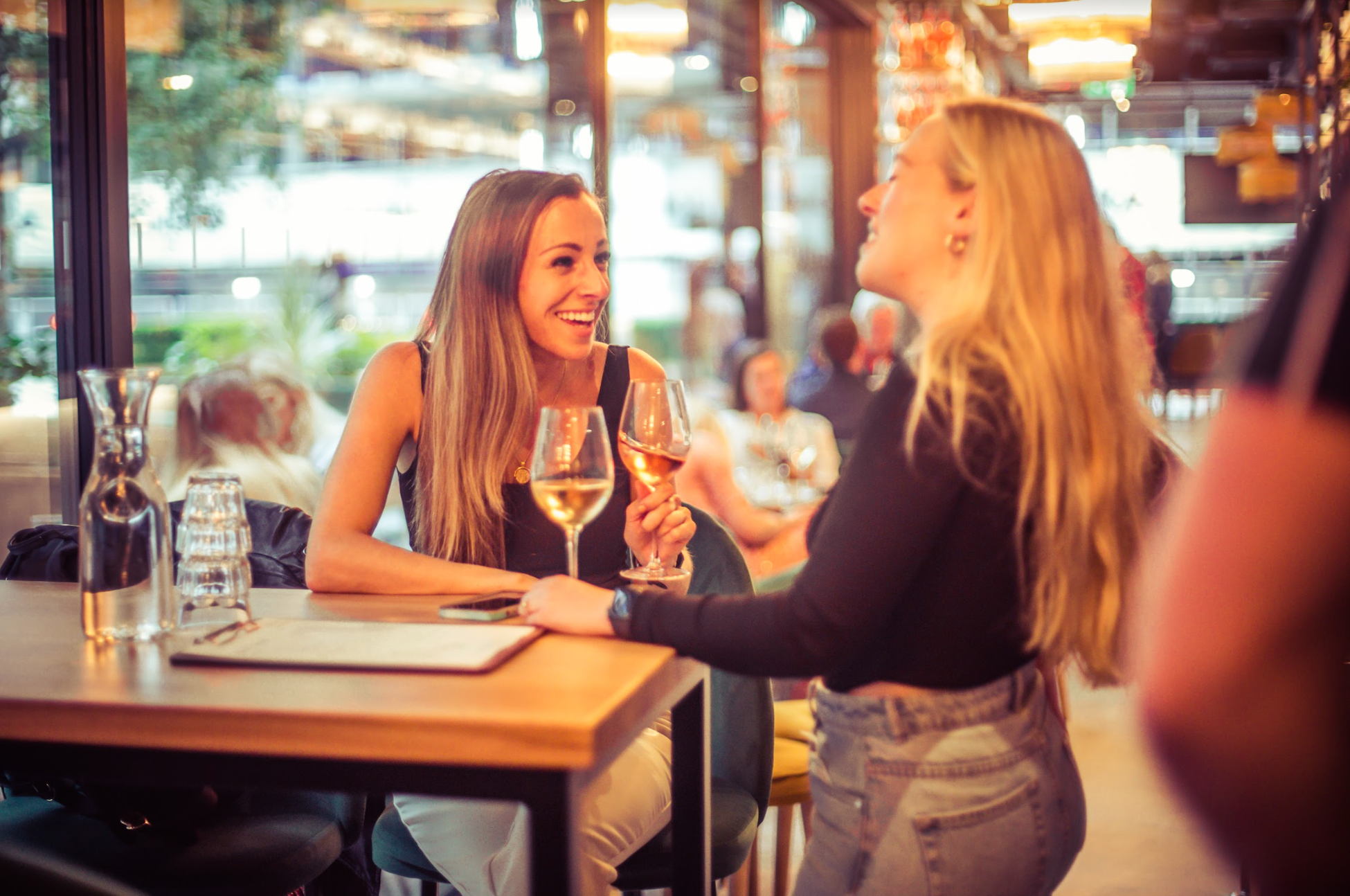 Two women chatting over drinks in vibrant Vagabond Shoreditch venue, ideal for networking.