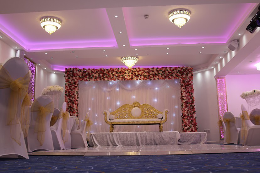 Elegant wedding venue with white chairs and floral backdrop at Oscaar Banqueting.