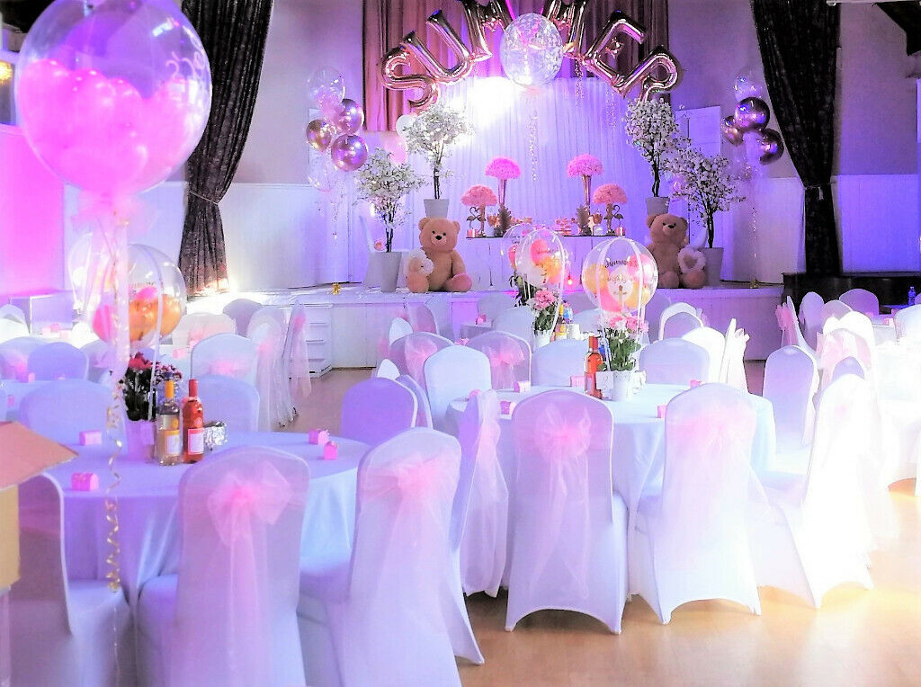 Vibrant event space with white tables and pink sashes for summer celebrations or children's parties.