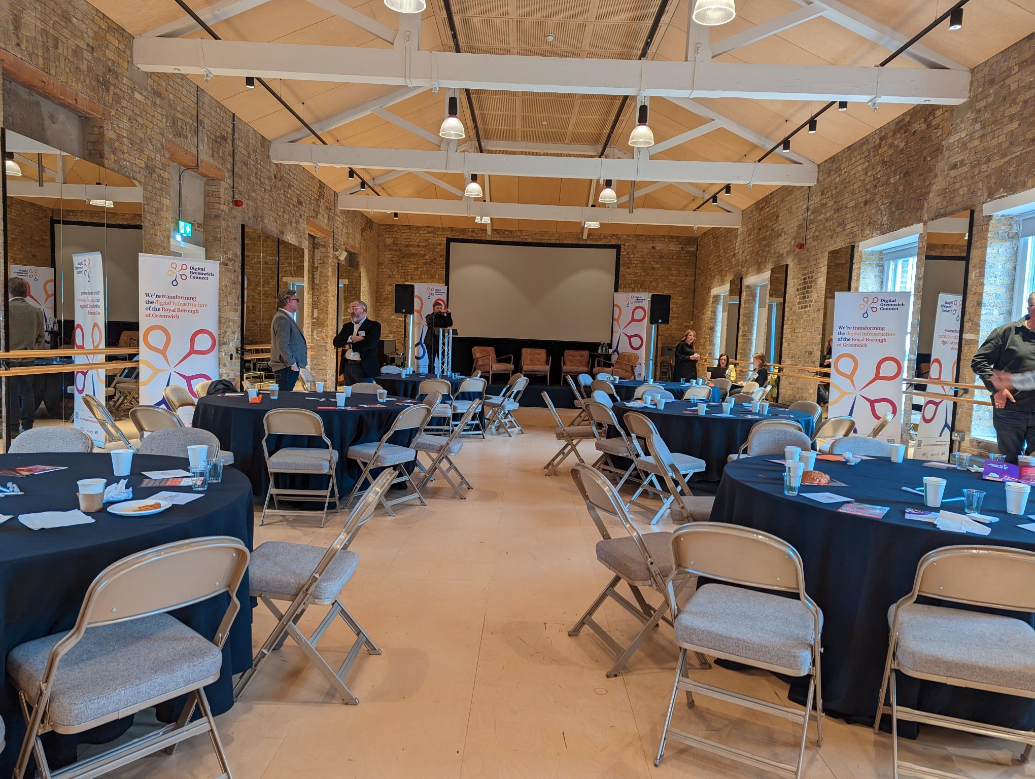 Event space at Woolwich Works with round tables, ideal for networking and presentations.