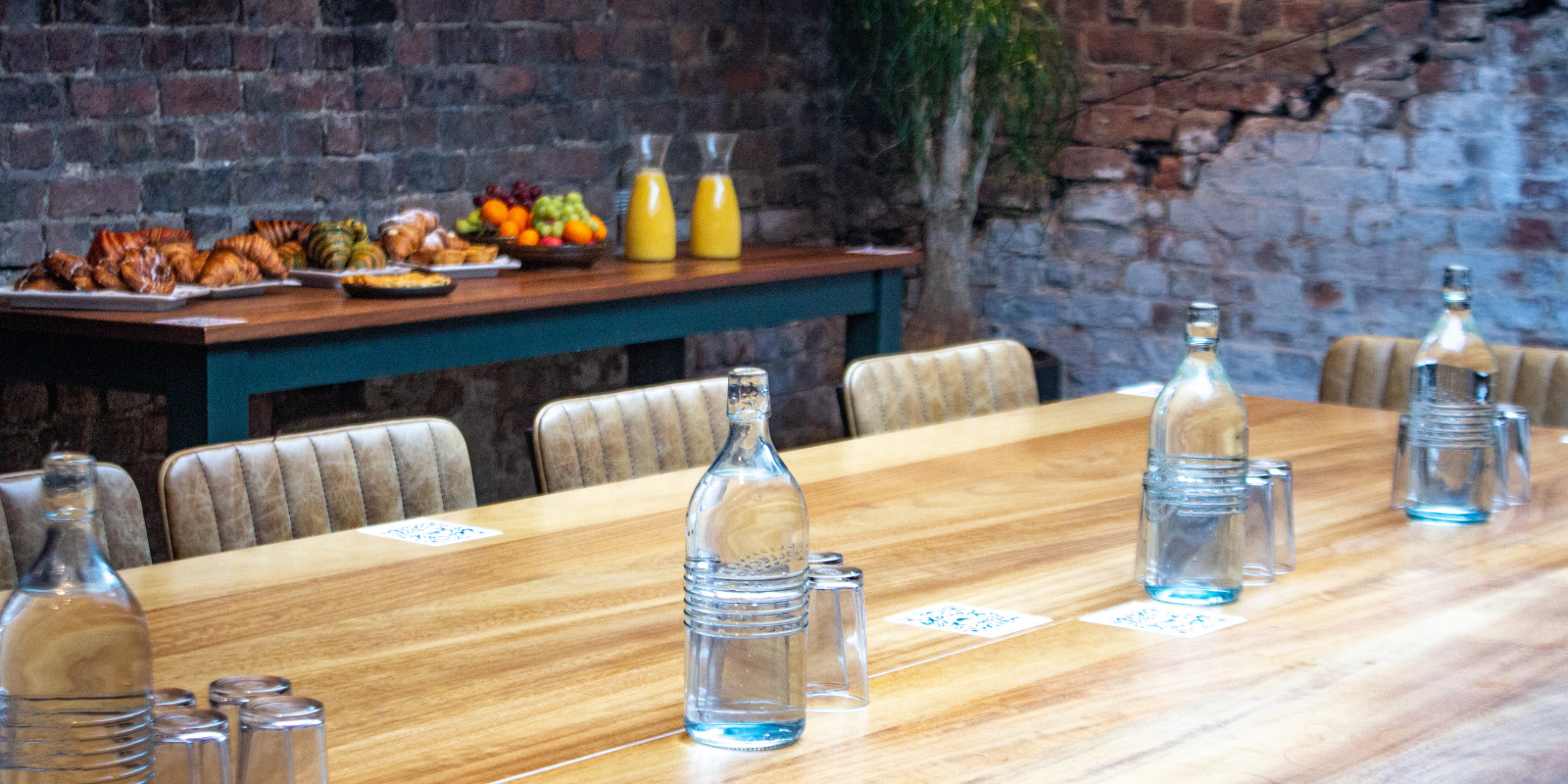 Meeting space with long wooden table and exposed brick at Duke Street Market.