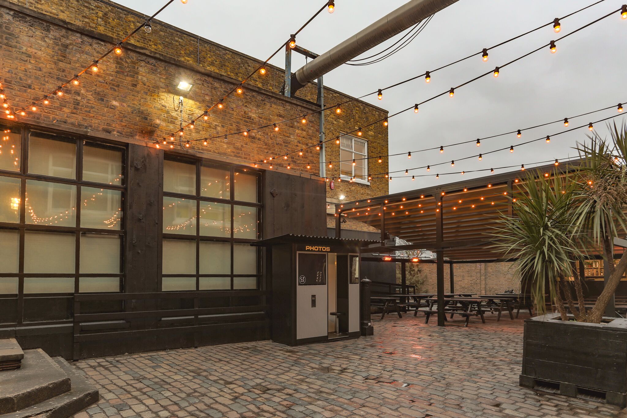 Outdoor event space at 93 Feet East with string lights and cobblestone flooring.