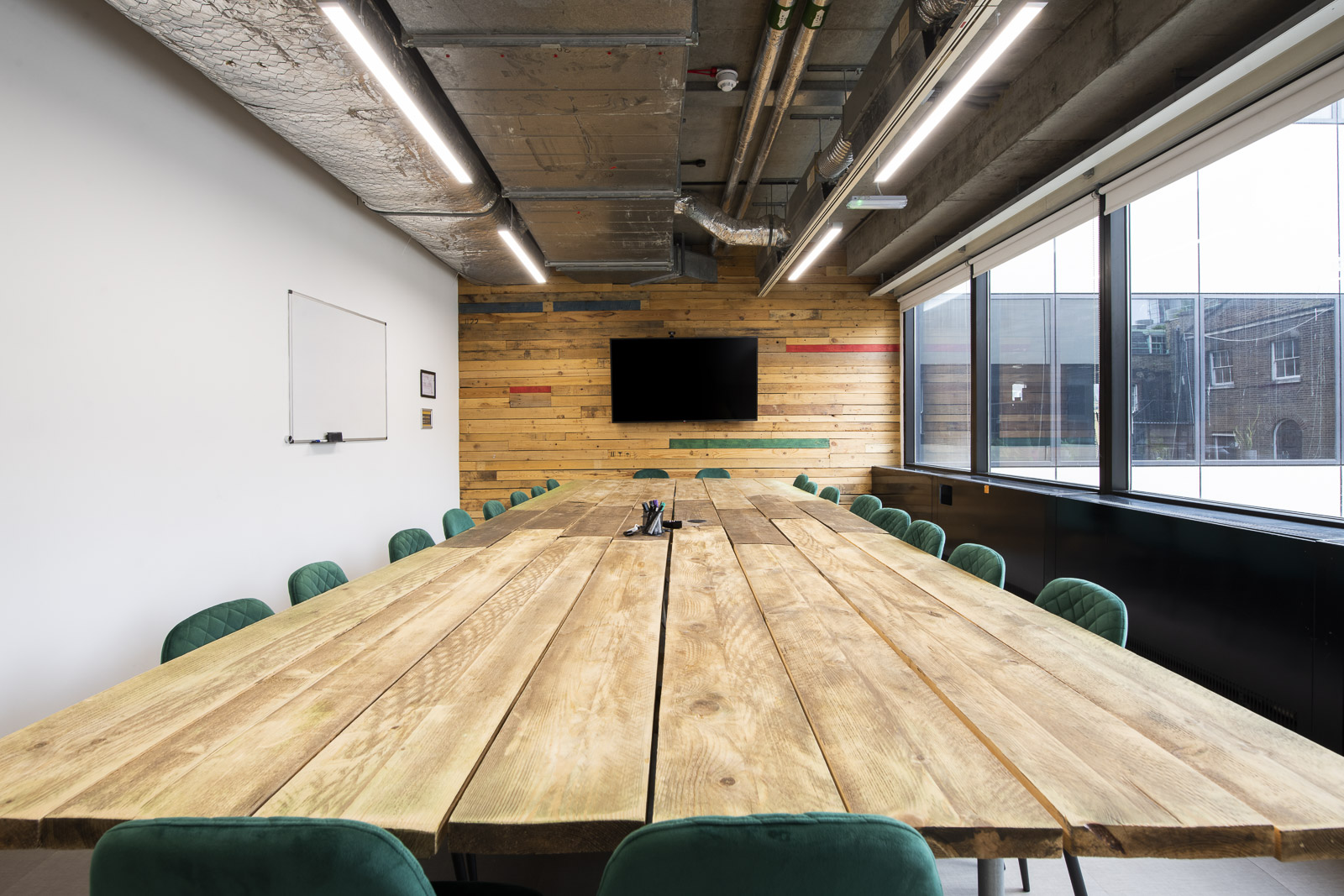 Modern meeting room with wooden table and green chairs at Runway East Borough Market.