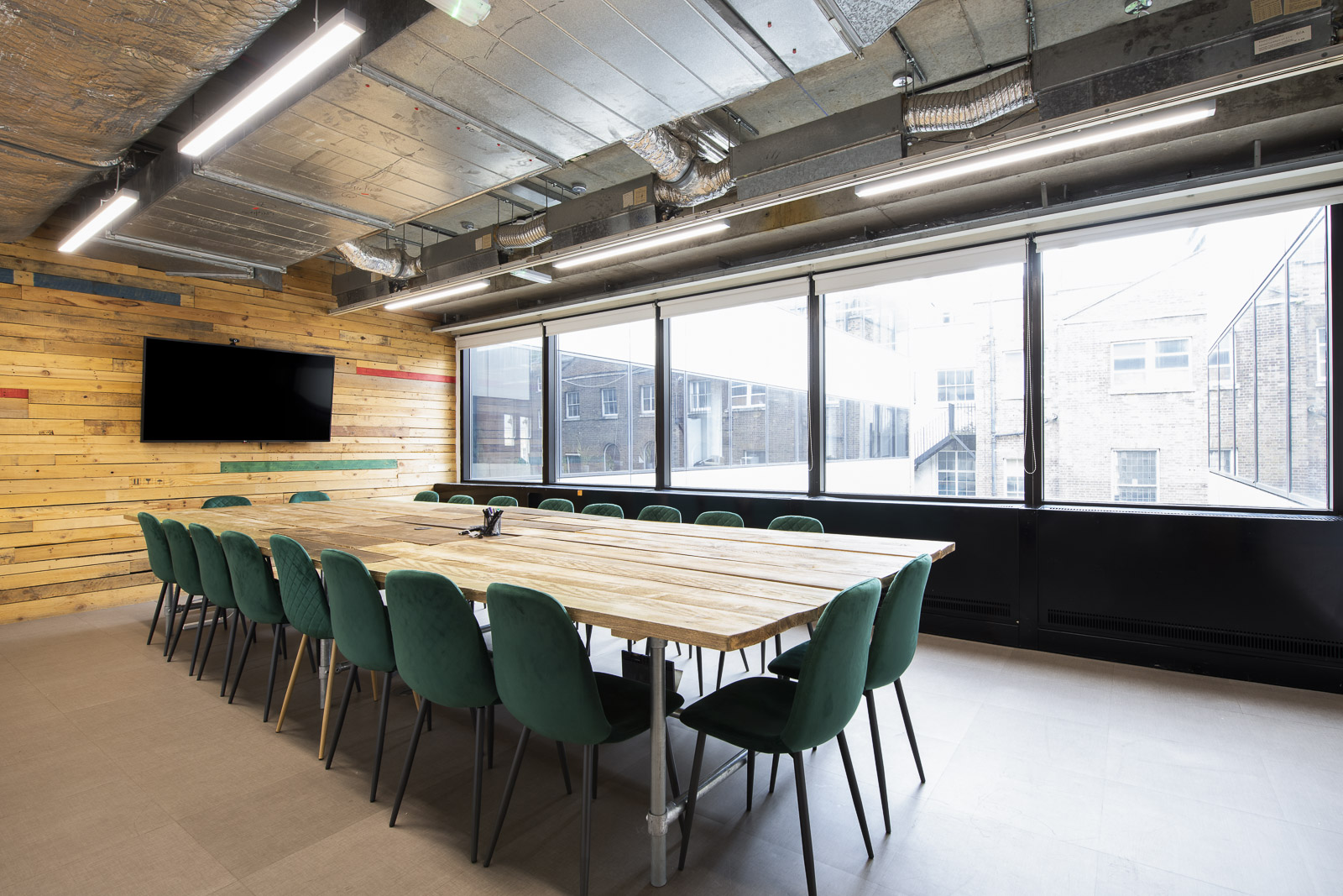 Modern meeting room with wooden table and green chairs at Runway East Borough Market.
