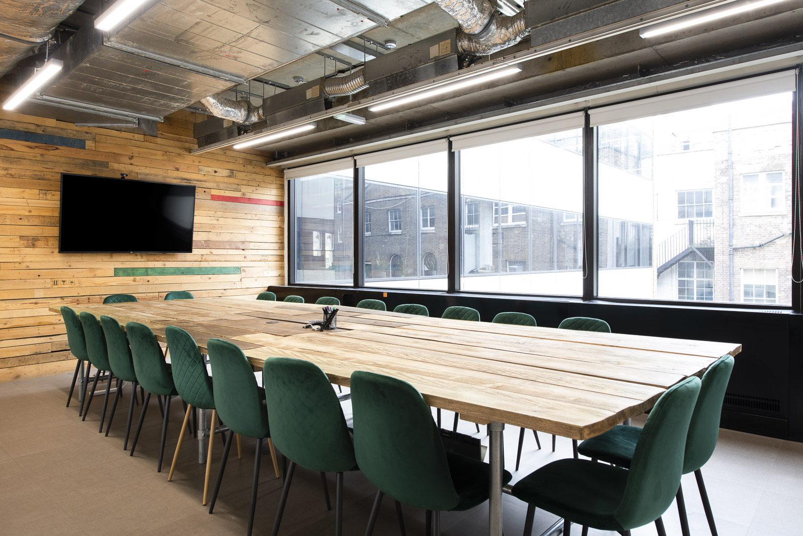 Modern conference room with wooden table and green chairs at Runway East Borough Market.