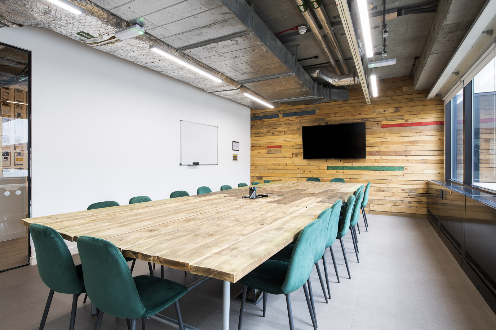 Modern meeting room with wooden table and green chairs at Runway East Borough Market.