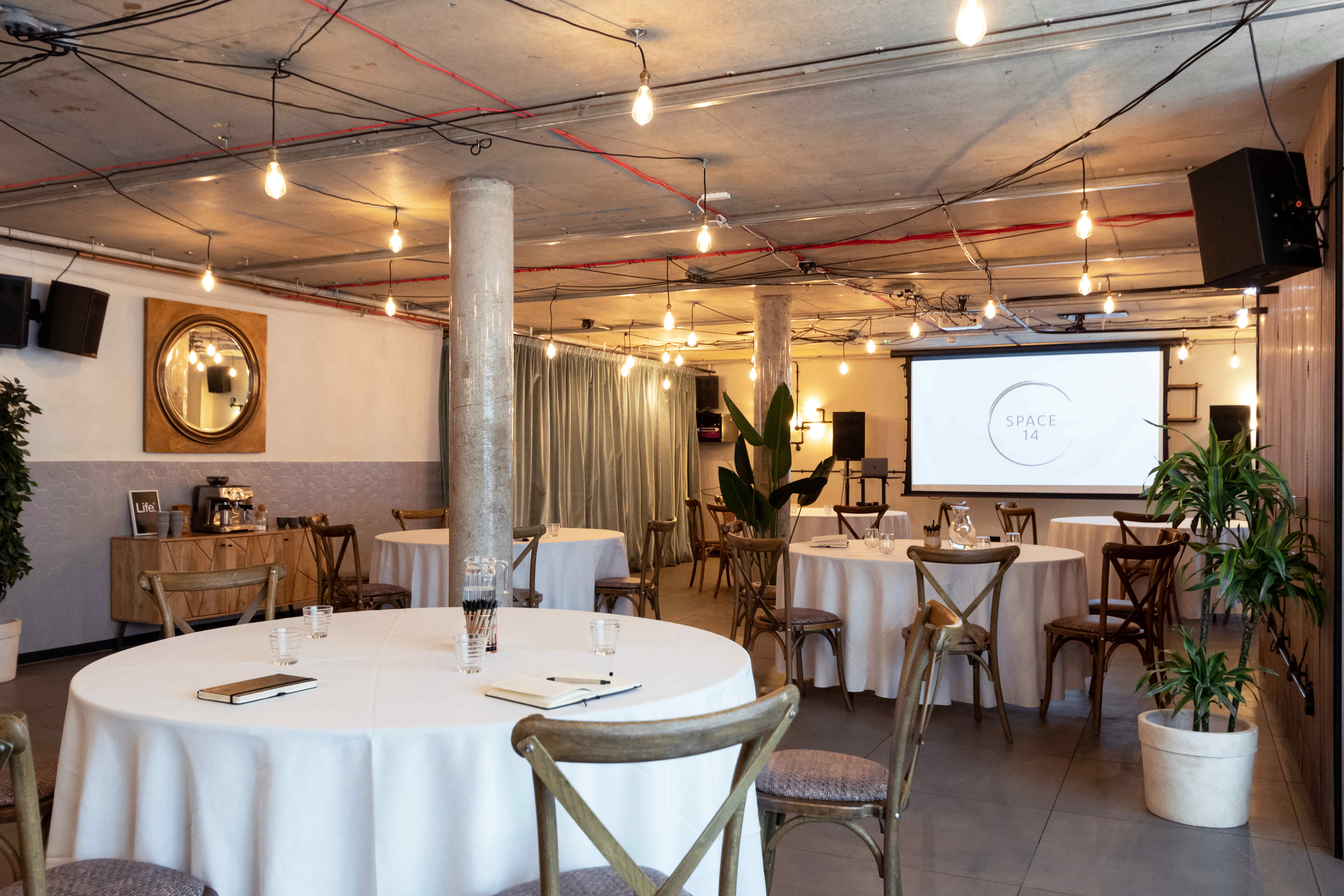 Versatile event space with round tables, ideal for meetings and workshops in a warm atmosphere.