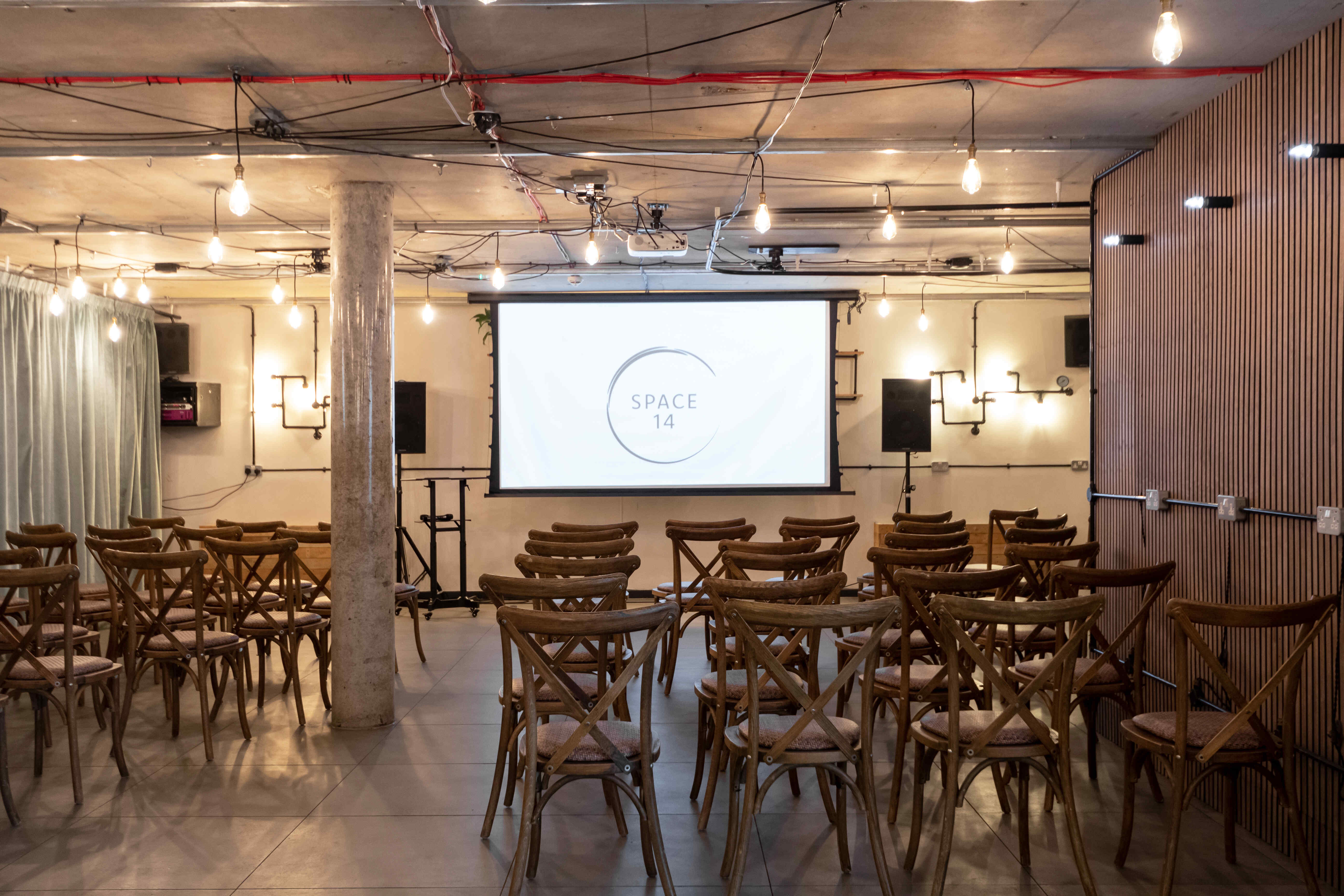 Versatile event space with wooden chairs, ideal for meetings and workshops at The Den in Space14.