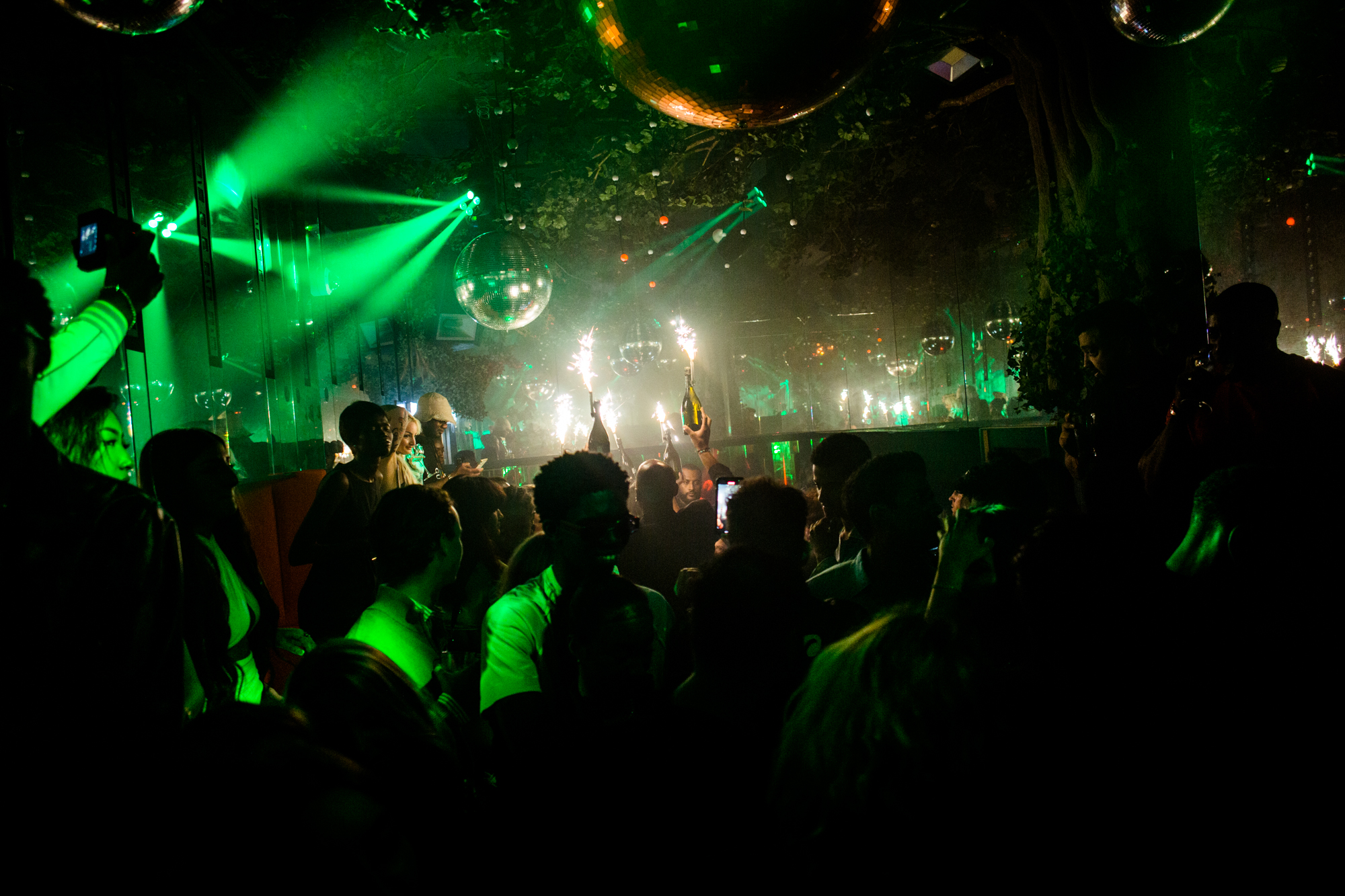 Vibrant Wyld Club event with green lighting, sparklers for nightlife and celebrations.