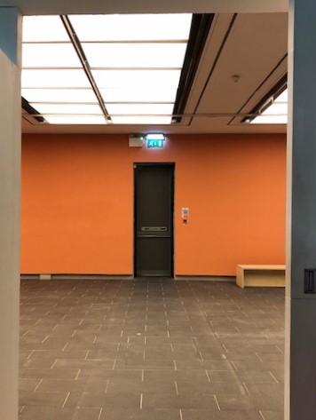 Minimalist event space with orange accent wall, ideal for meetings and gatherings.