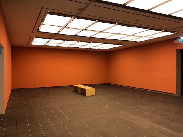 Versatile event space with orange walls, ideal for workshops and gatherings.