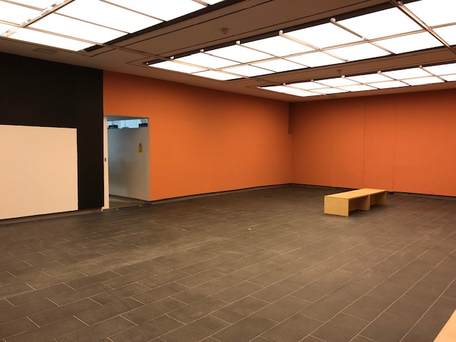 Versatile event space with orange accent wall, perfect for workshops and gatherings.