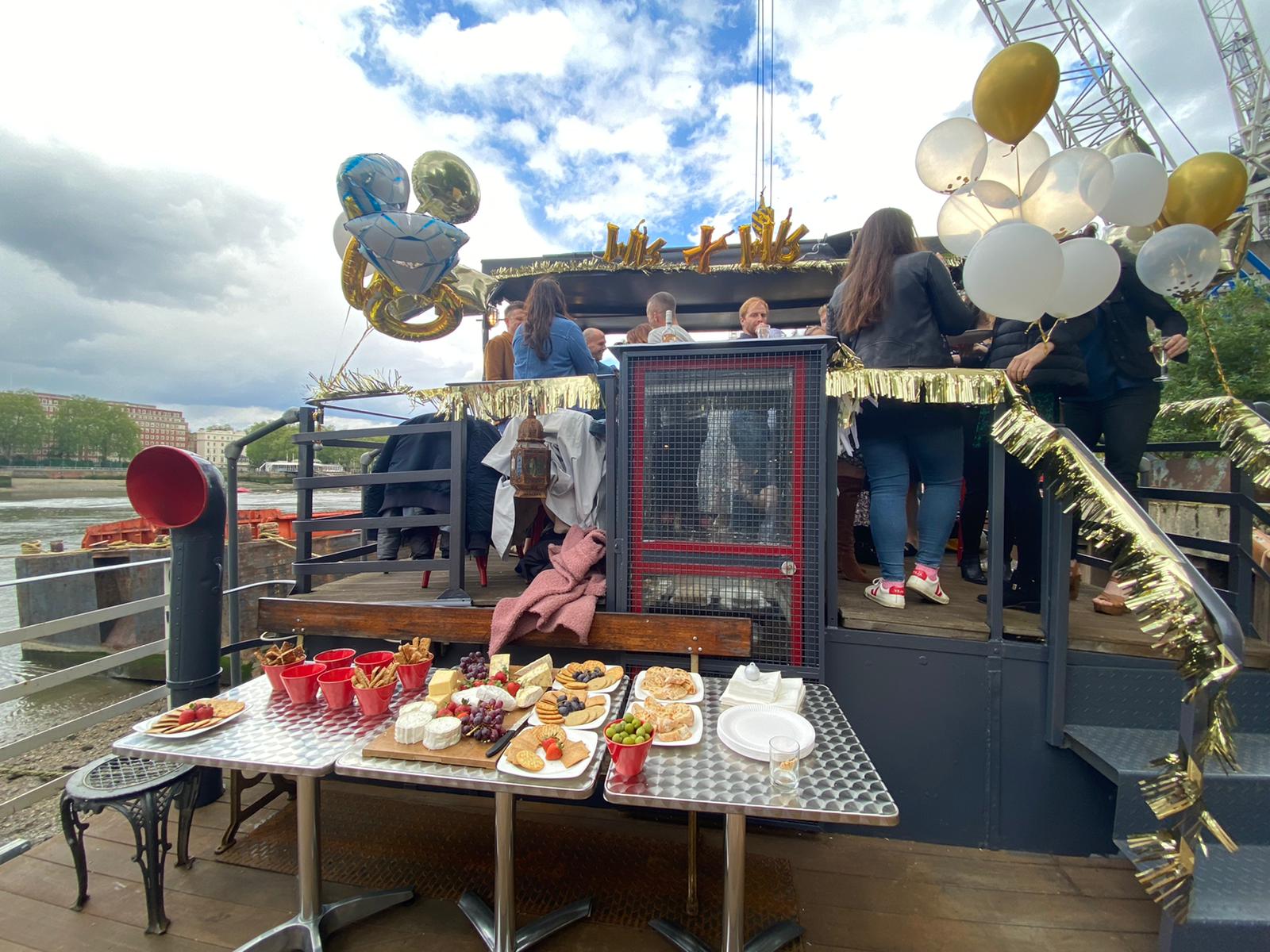 Outdoor East Deck on Battersea Barge, vibrant event with festive decor and appetizers.