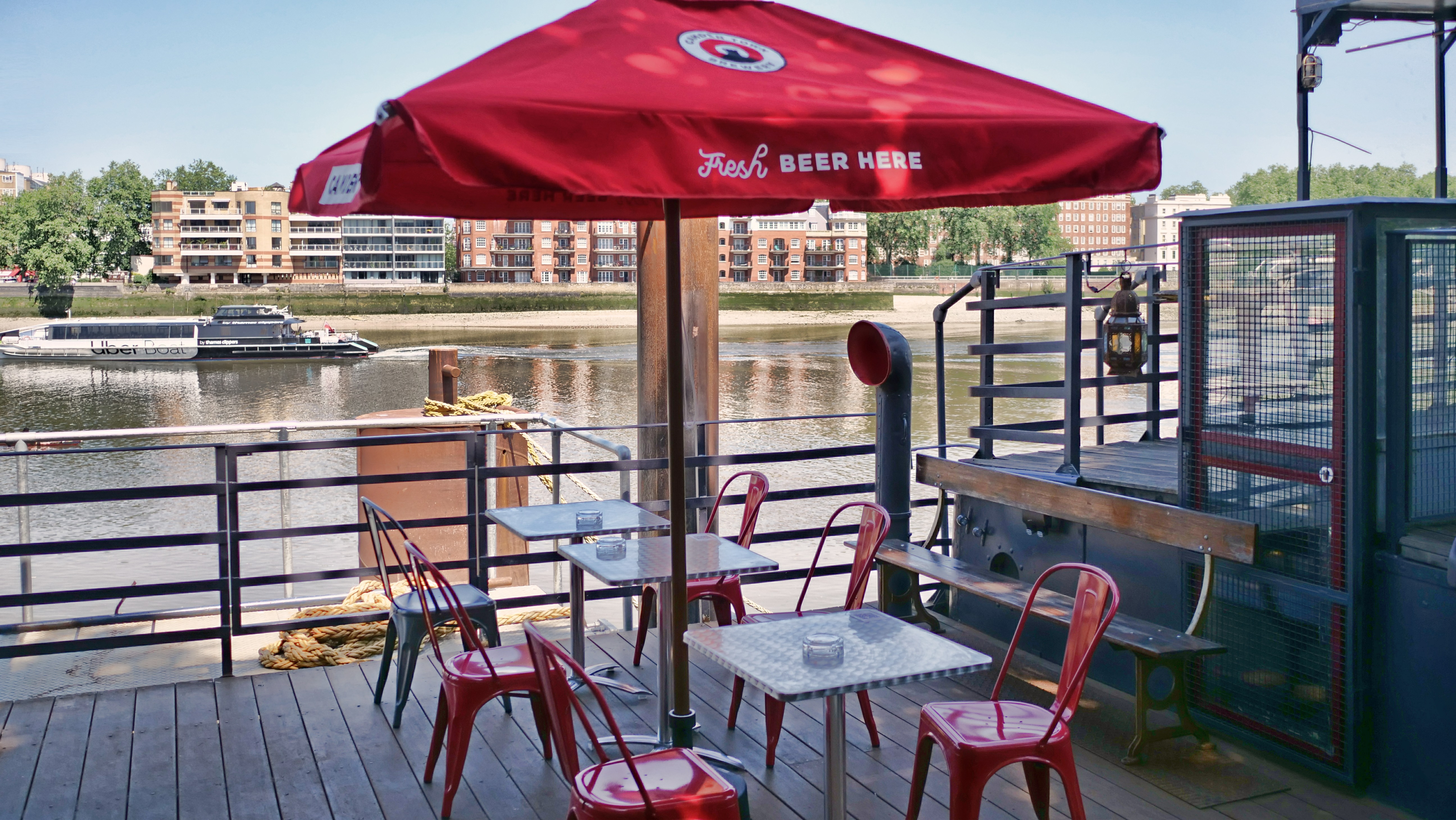 Uncovered Terrace at Battersea Barge with red umbrella, ideal for networking events.