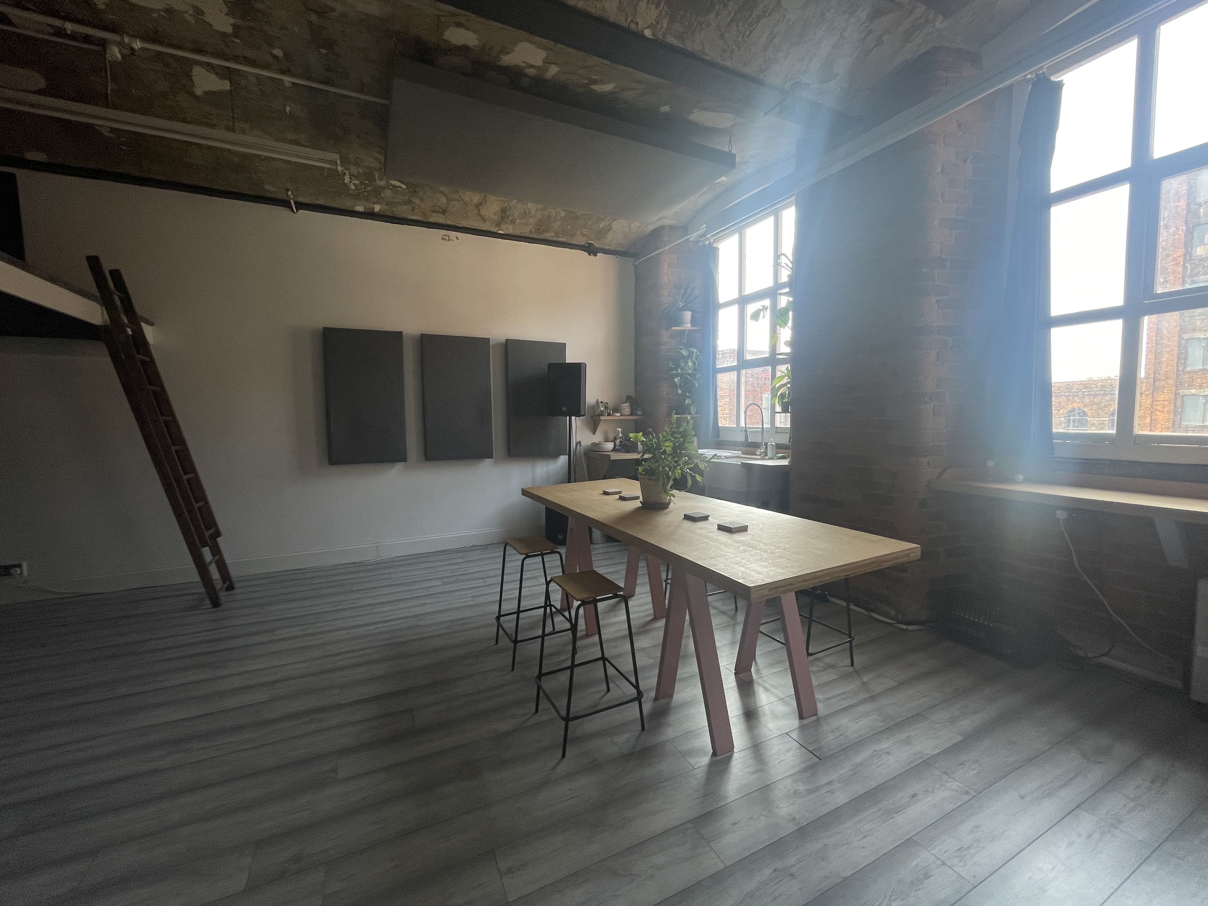 Modern industrial meeting space with large windows, ideal for workshops and presentations.