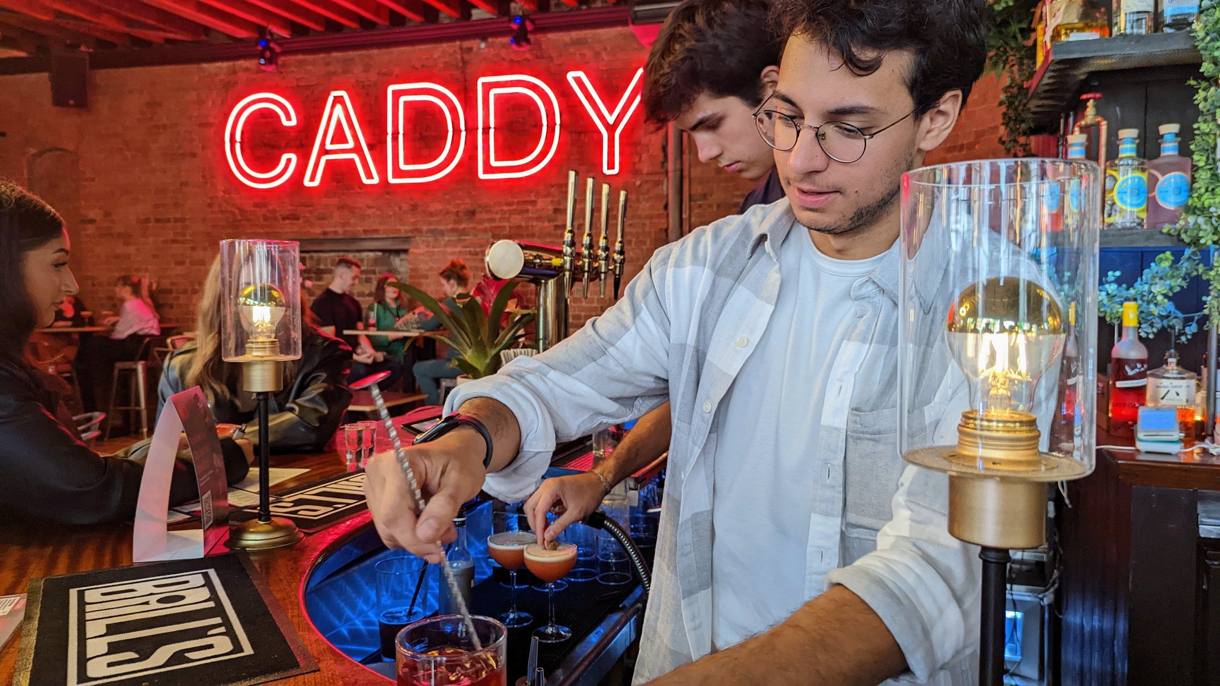 Vibrant Shoreditch bar scene with illuminated "CADDY" sign for networking events.