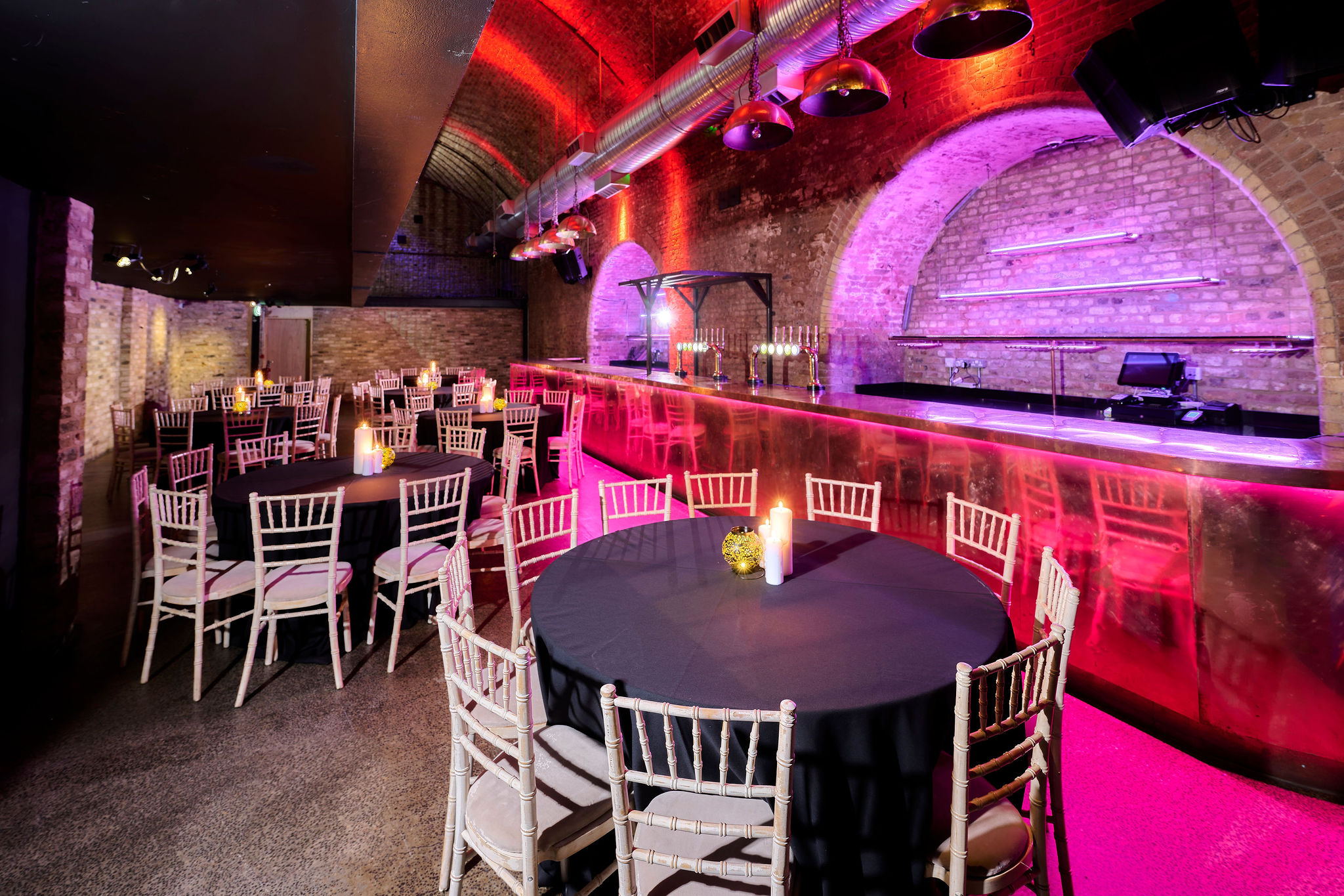 Stylish event space with round tables and purple lighting at The Steel Yard.
