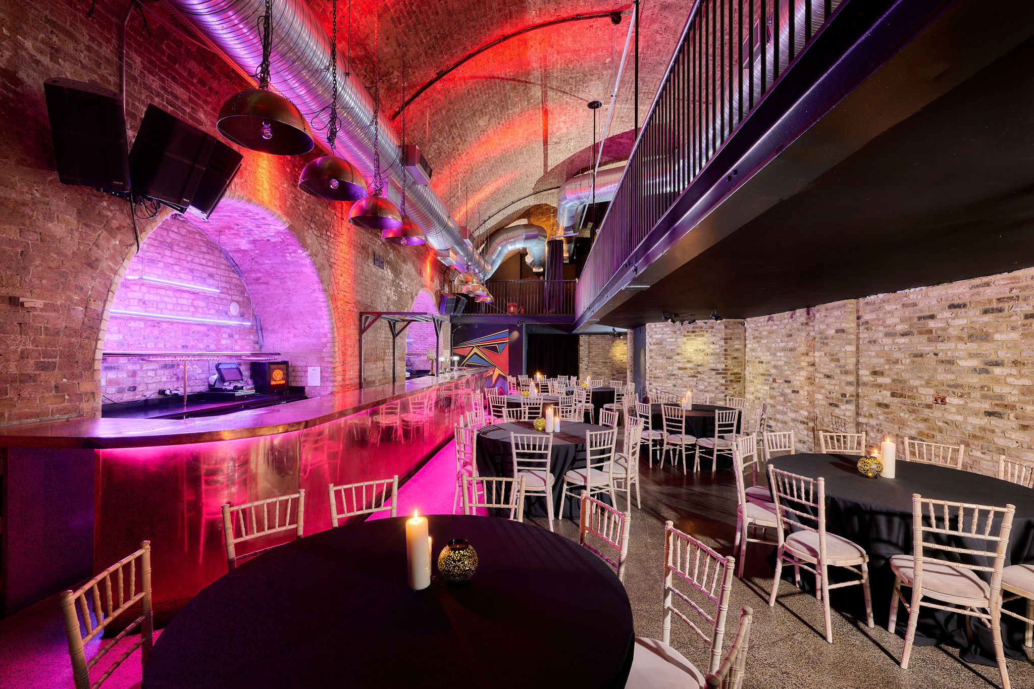 Stylish event space with exposed brick and vibrant lighting for corporate gatherings.