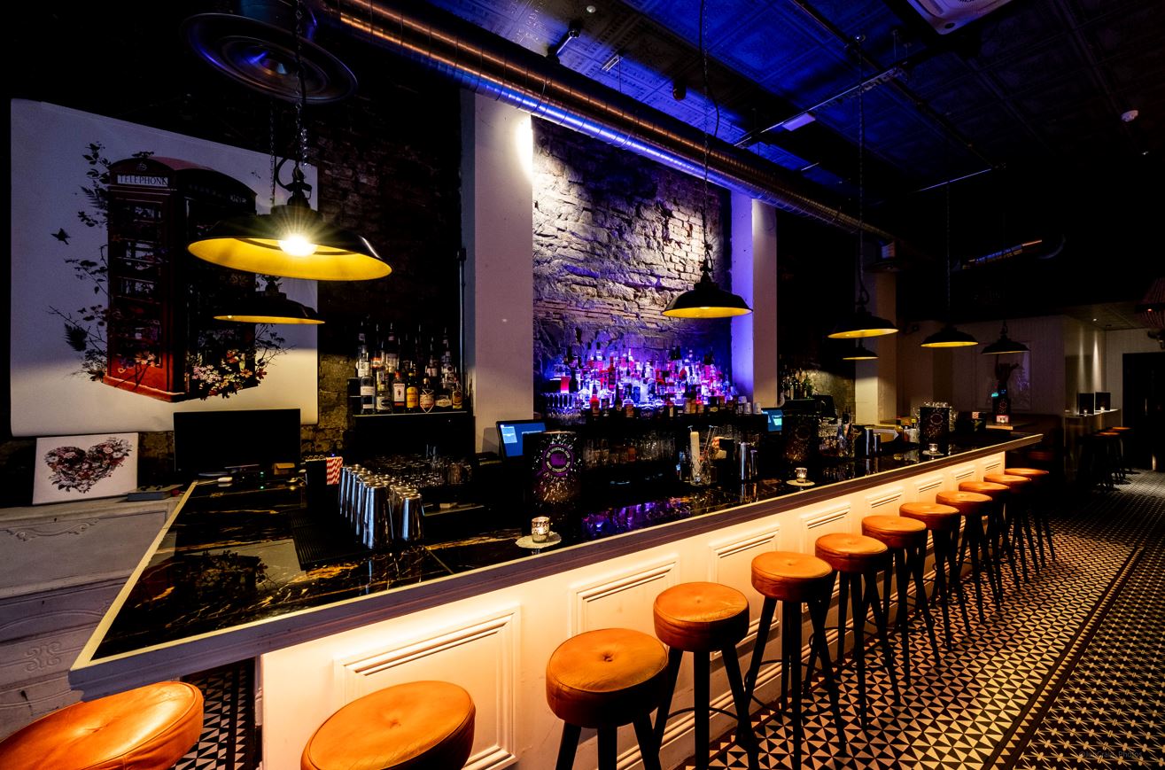 Stylish bar area with black countertop and orange stools for networking events in Bristol.