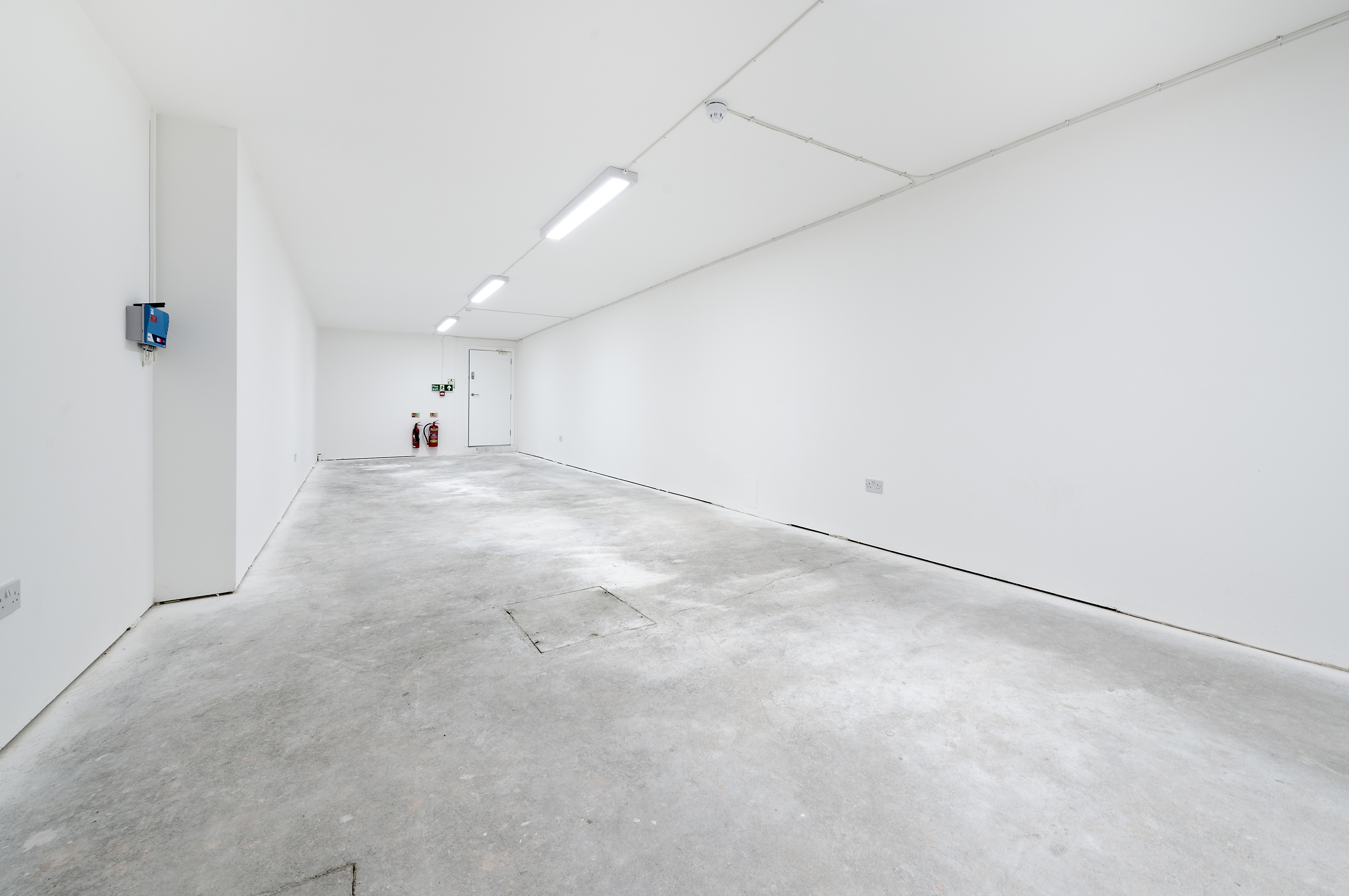 Minimalist event space with white walls and concrete floor, perfect for creative setups.