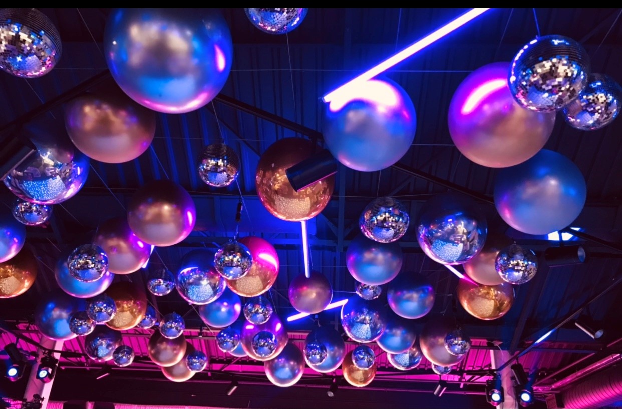 Vibrant event space with disco balls and neon lights for parties and celebrations.