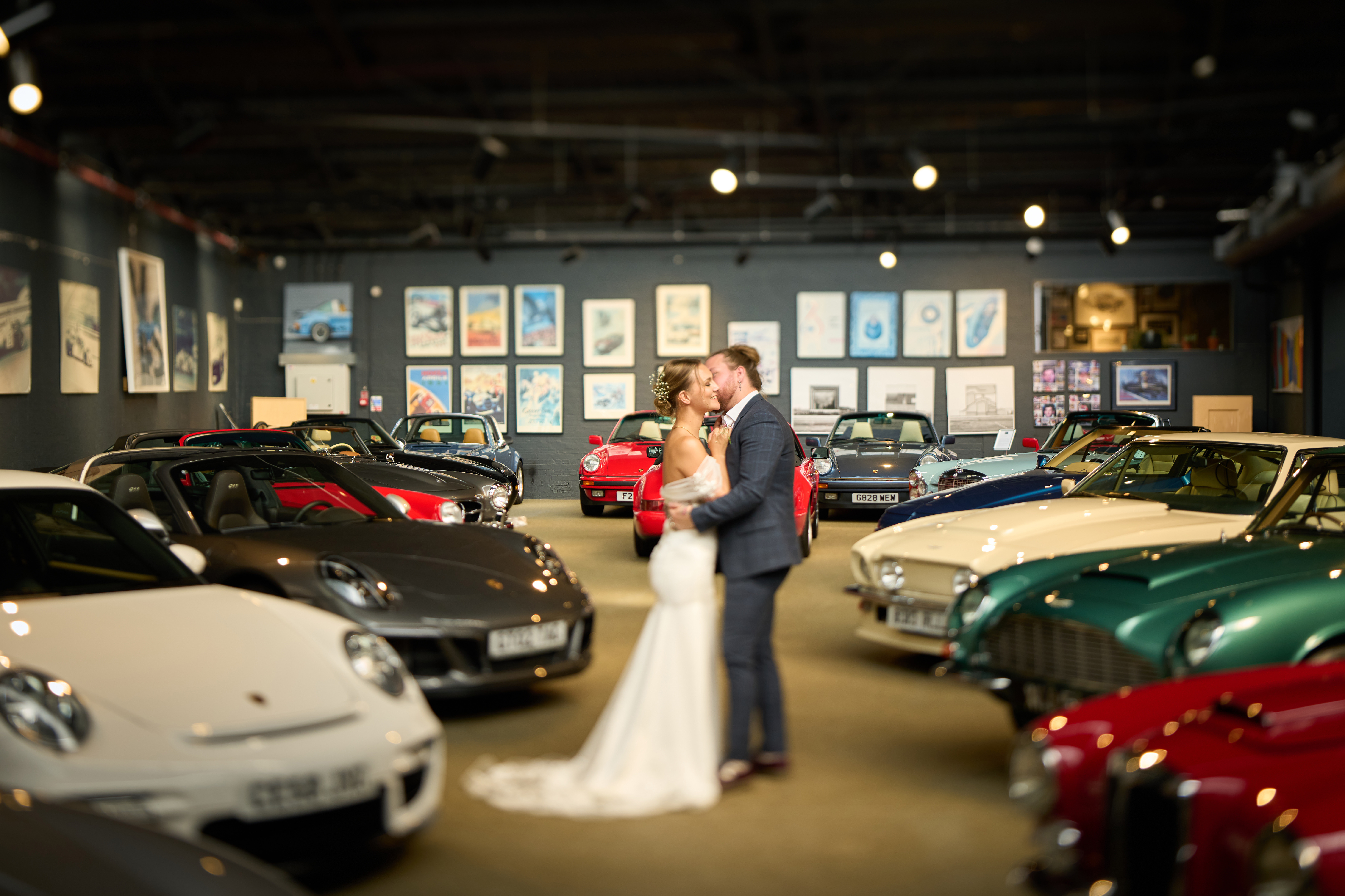 Elegant wedding venue in upscale car gallery with classic cars backdrop.