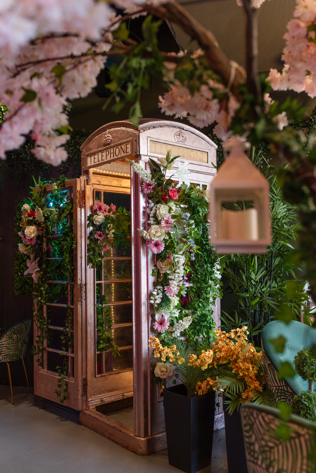 Vintage telephone booth adorned with flowers for themed events and photo opportunities.