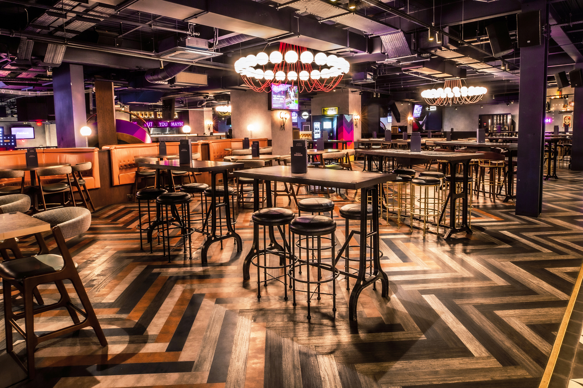 Christmas event space at Puttshack Watford with stylish high-top tables and unique lighting.