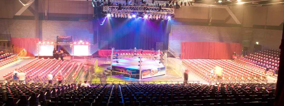 Wrestling match setup in The International Hall, vibrant lighting and optimal seating.