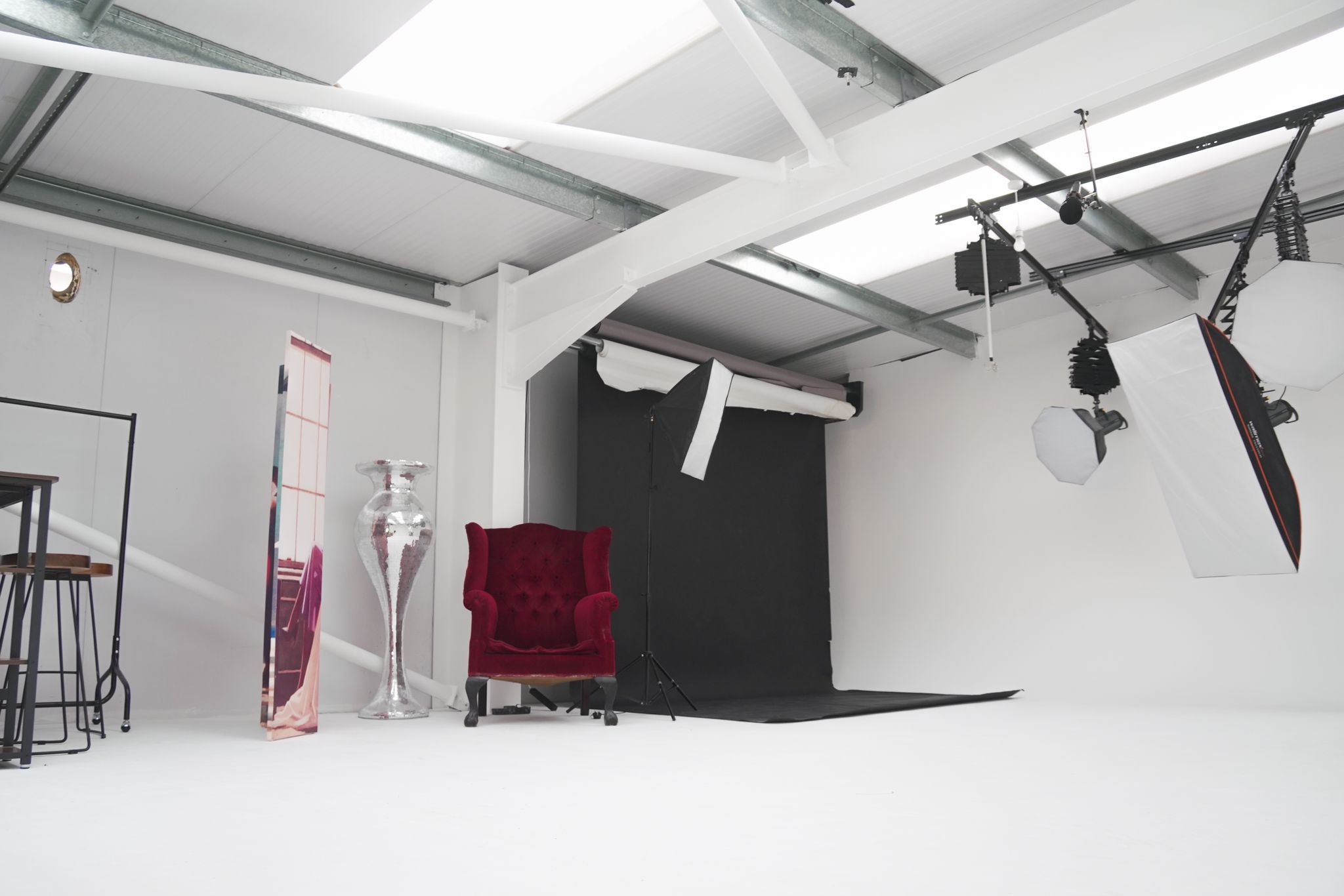 Versatile event space with minimalist backdrop and plush red chair for creative gatherings.