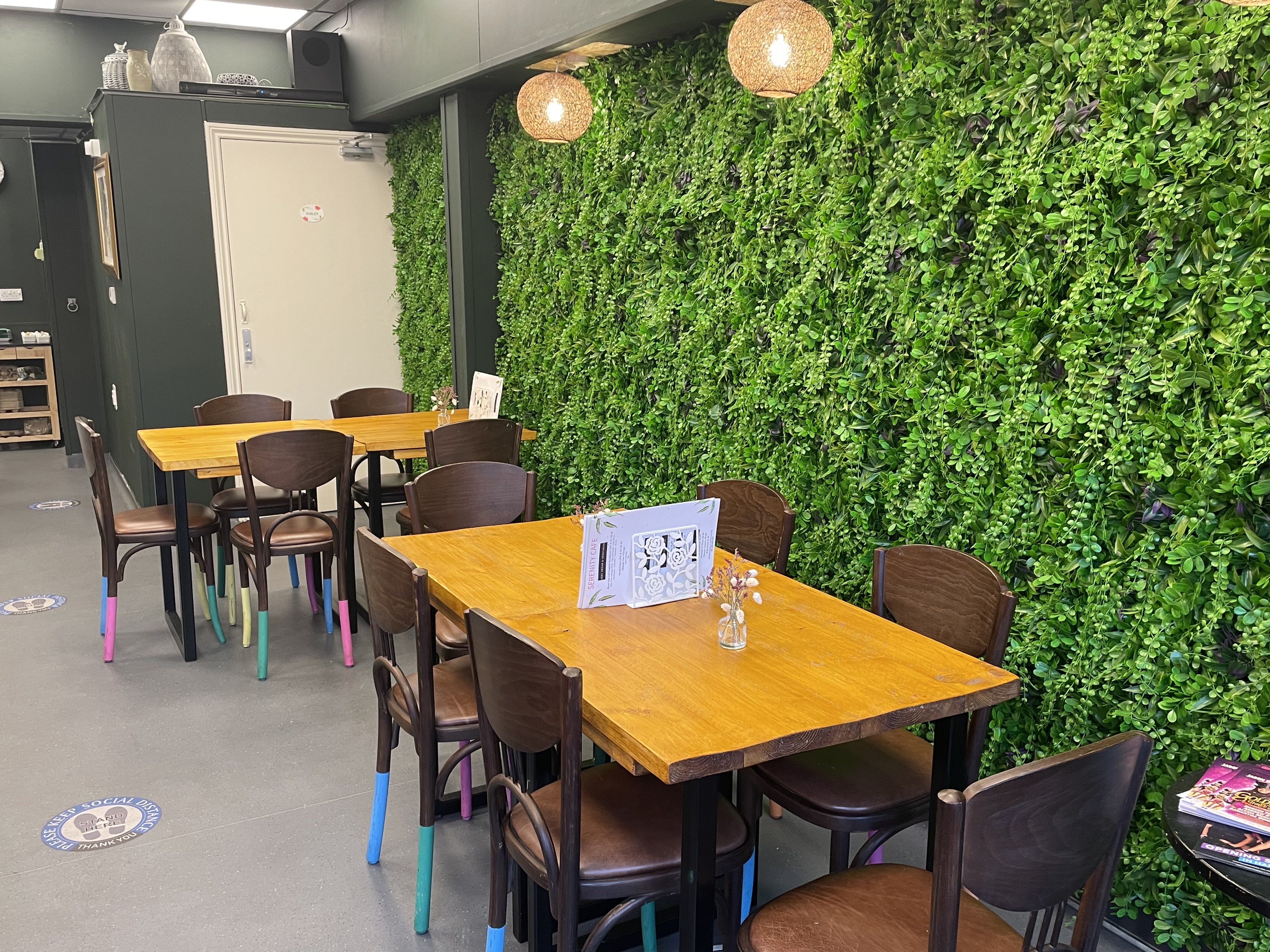 Cozy meeting space at Serenity Cafe with a green living wall for workshops and gatherings.
