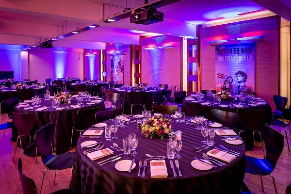 HCA Auditorium set for formal dinner with elegant tables and ambient lighting.