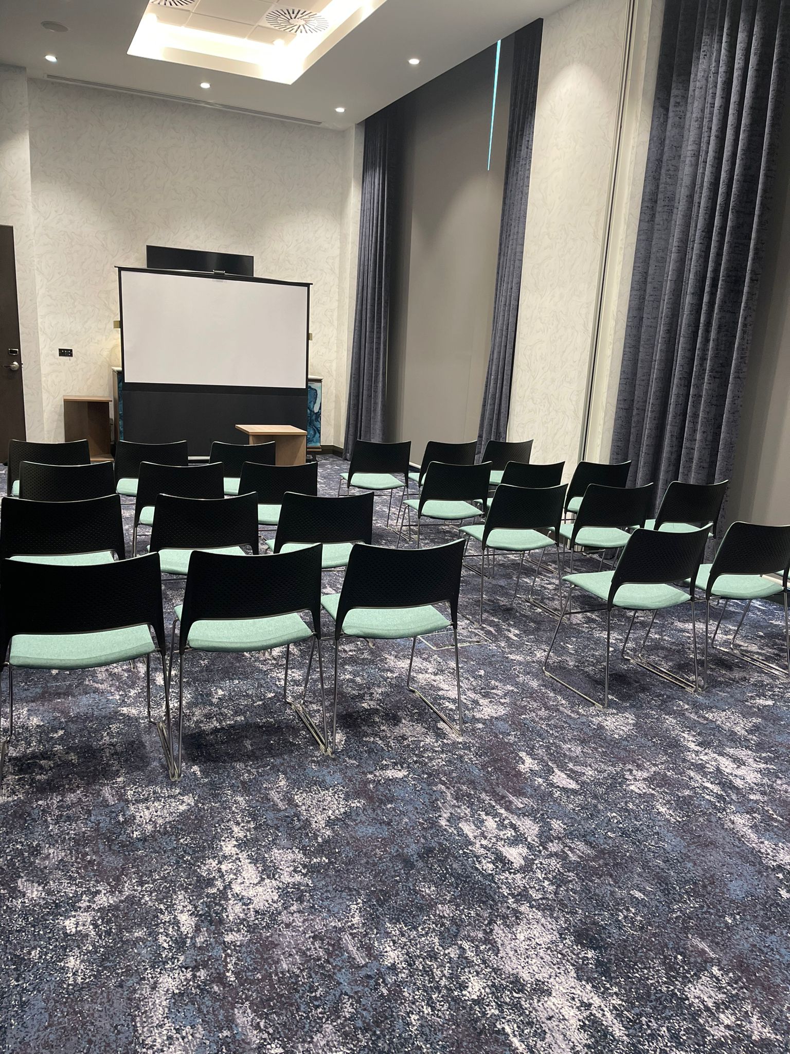 Stoneywood Suite meeting room with black chairs and projection screen at Hilton Aberdeen TECA.