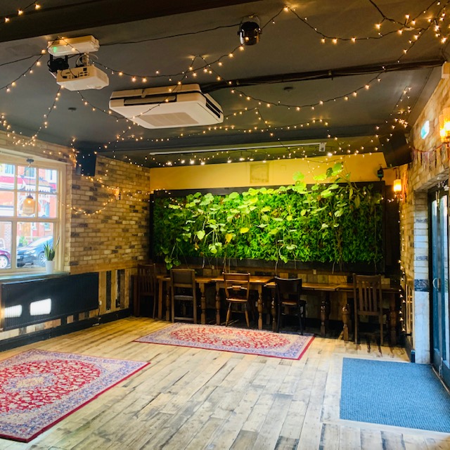 Charming Function Room with lush green wall for intimate gatherings and creative meetings.