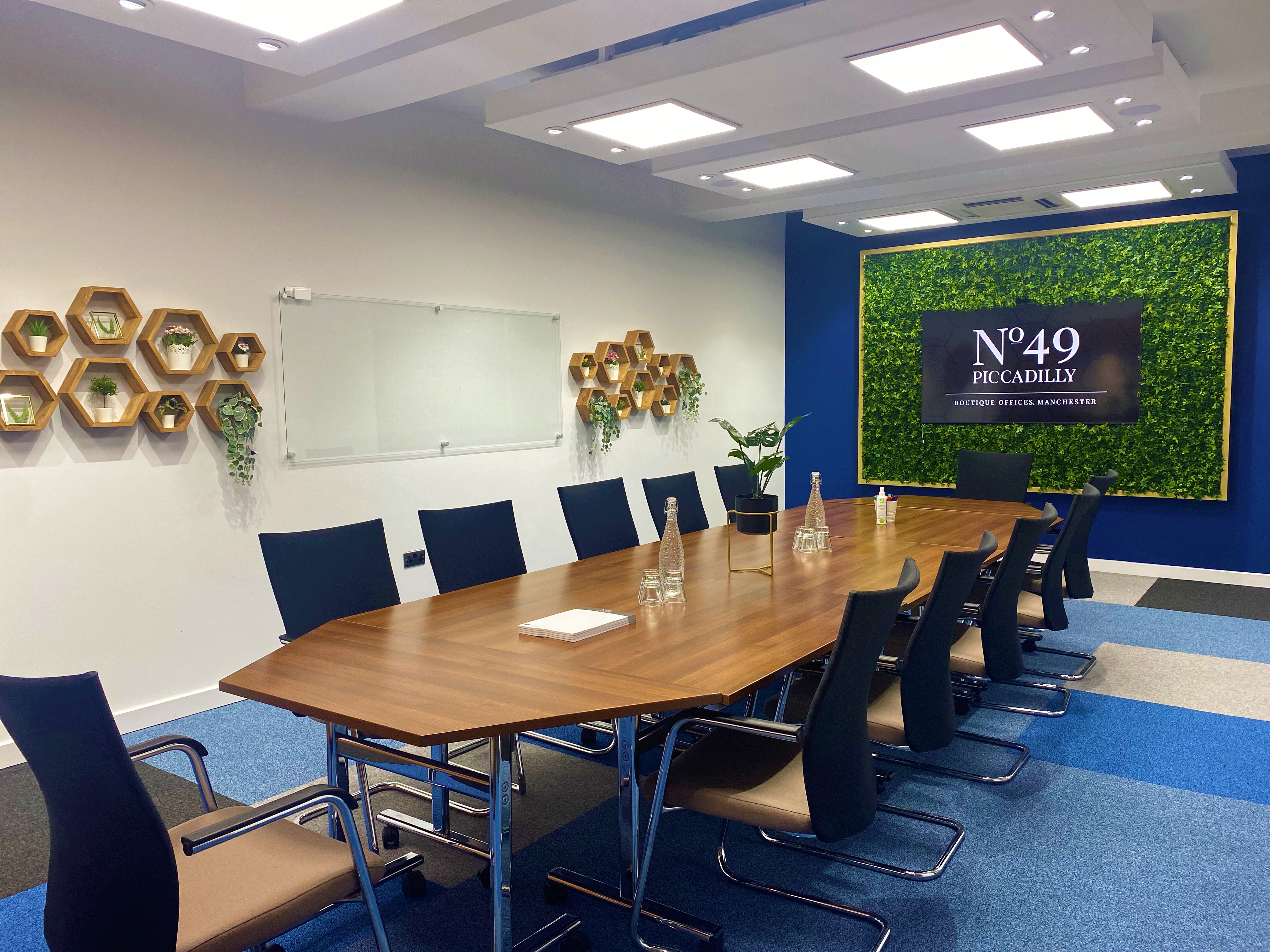 Modern conference room at Crompton, featuring a large wooden table and greenery accents.